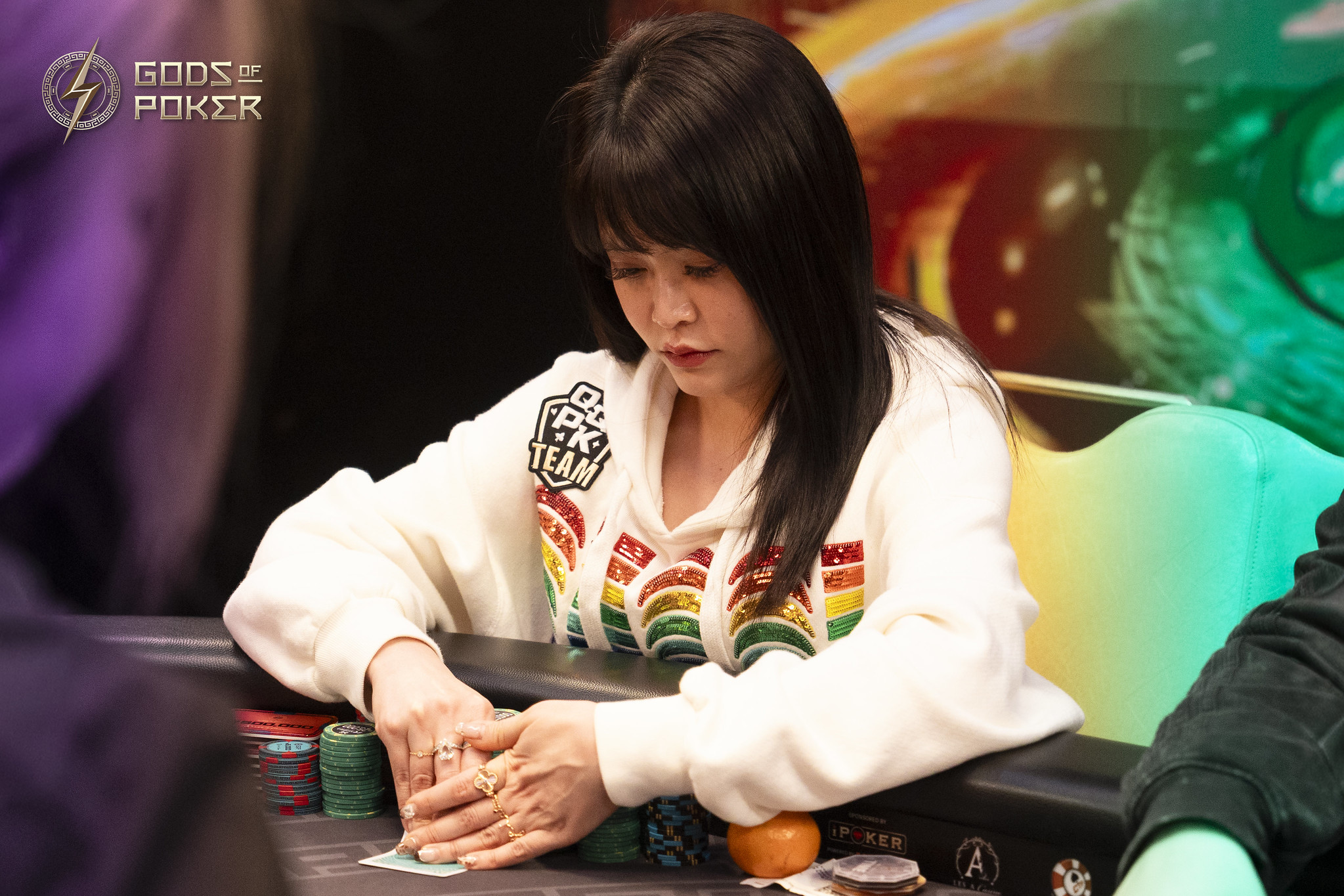 A young woman at a poker table intently examining her cards during a game.