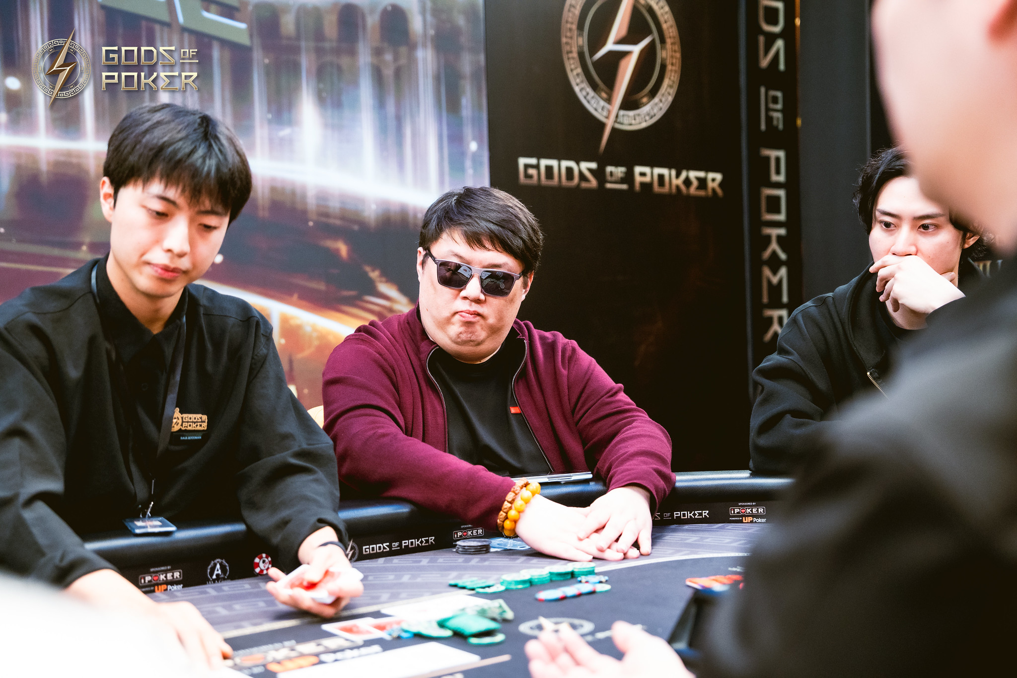 Three men intently playing poker at a table with prominent
