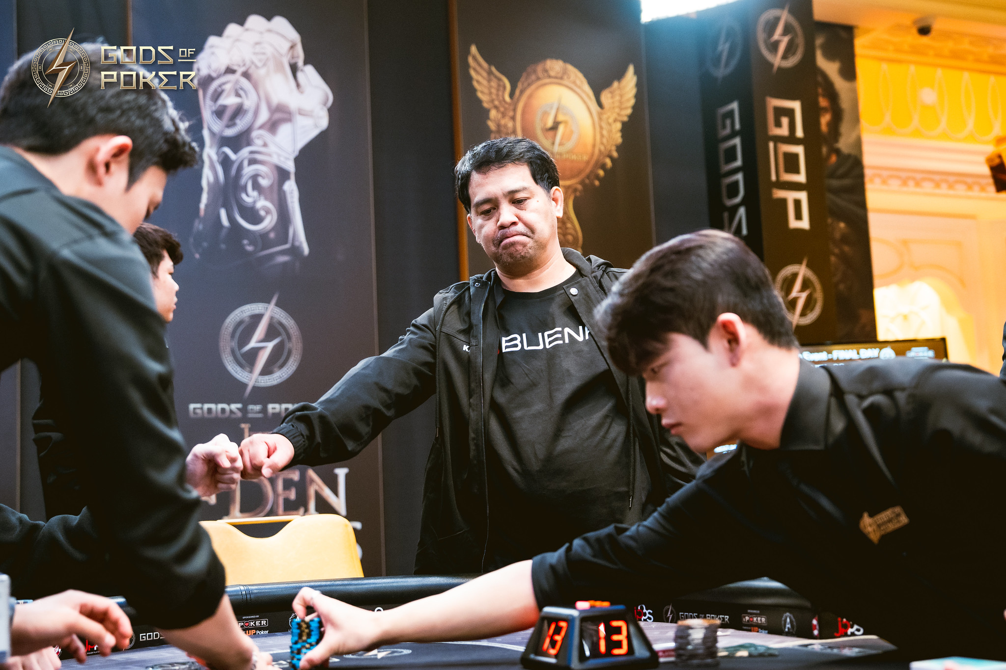 Three men at a casino game table, one supervising, two players handling chips.