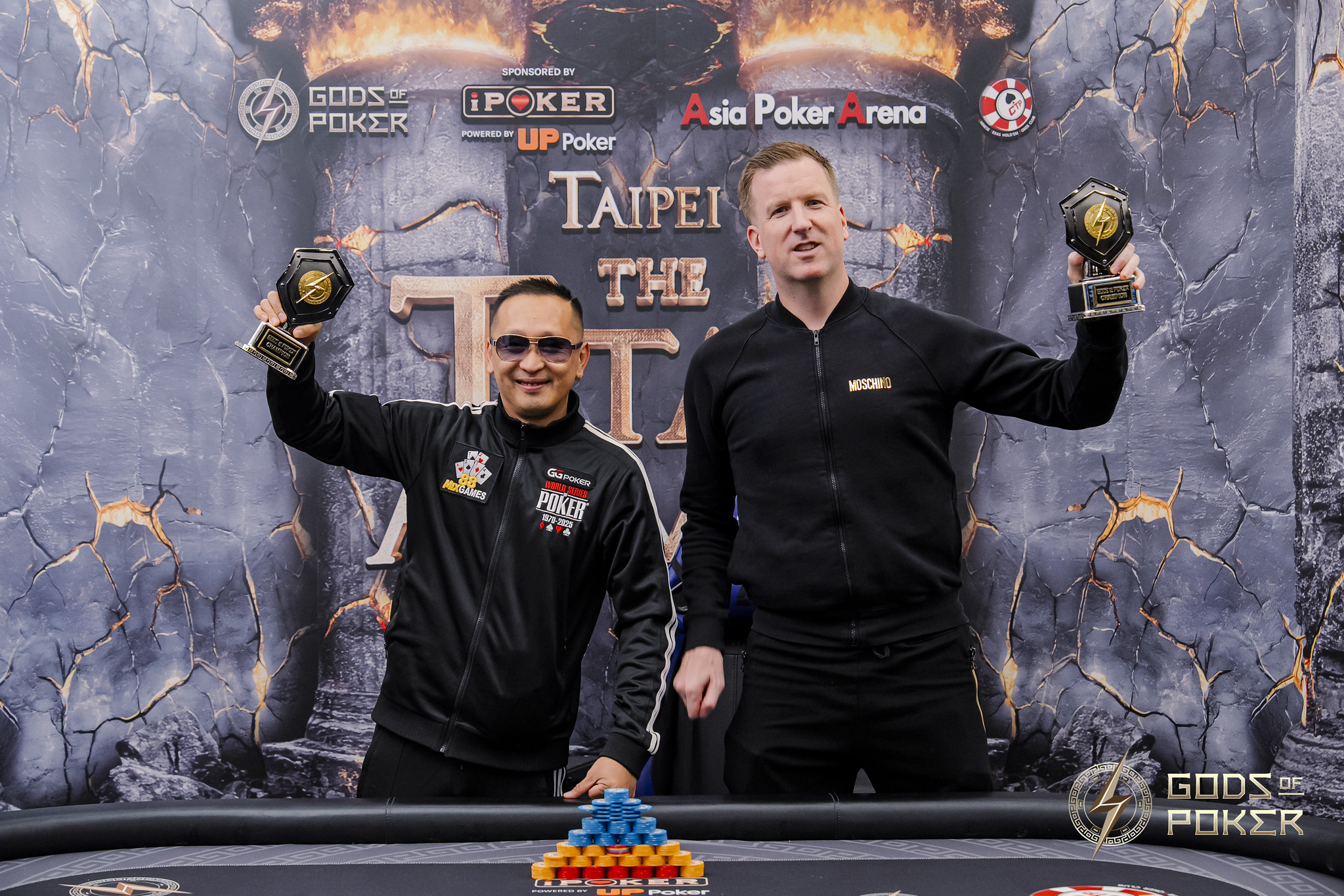 Two triumphant poker players proudly hold their winner's trophies after a successful tournament.