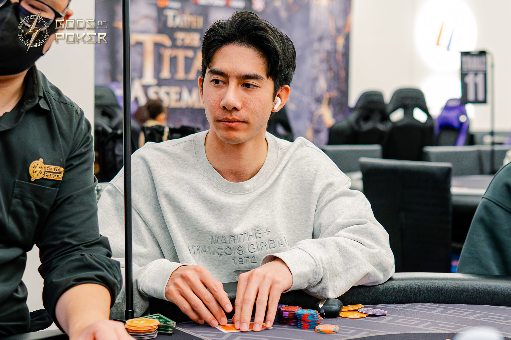Young man playing poker, concentrating on his hand with chips and cards before him.