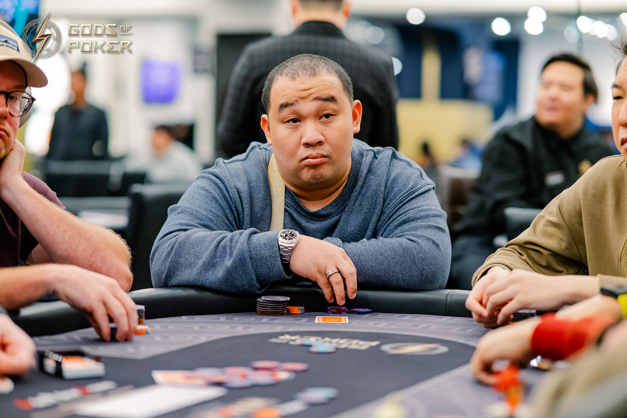 Asian man with a serious expression playing poker at a casino table.