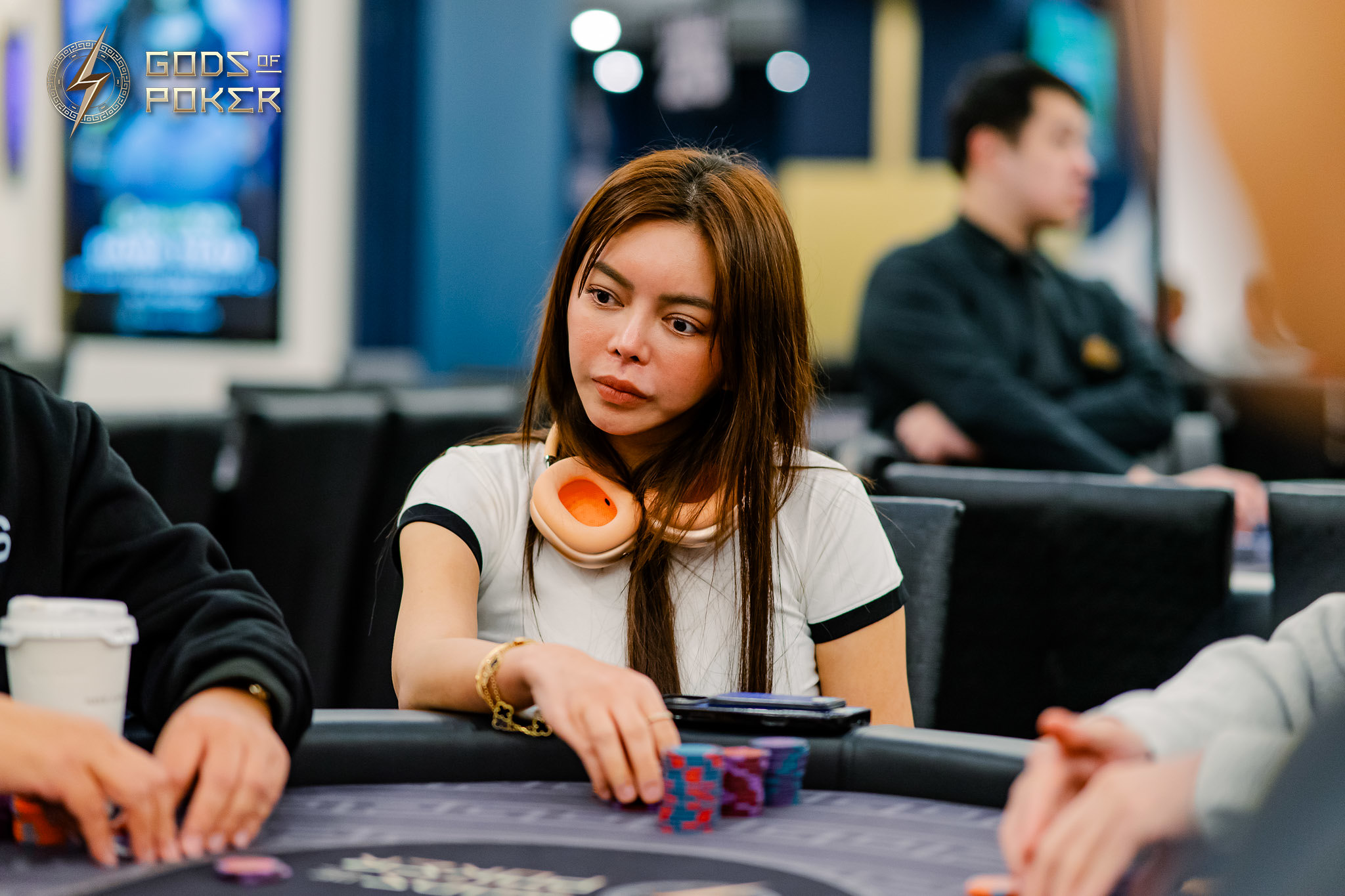 Woman with orange headphones, intently playing poker at a casino table.