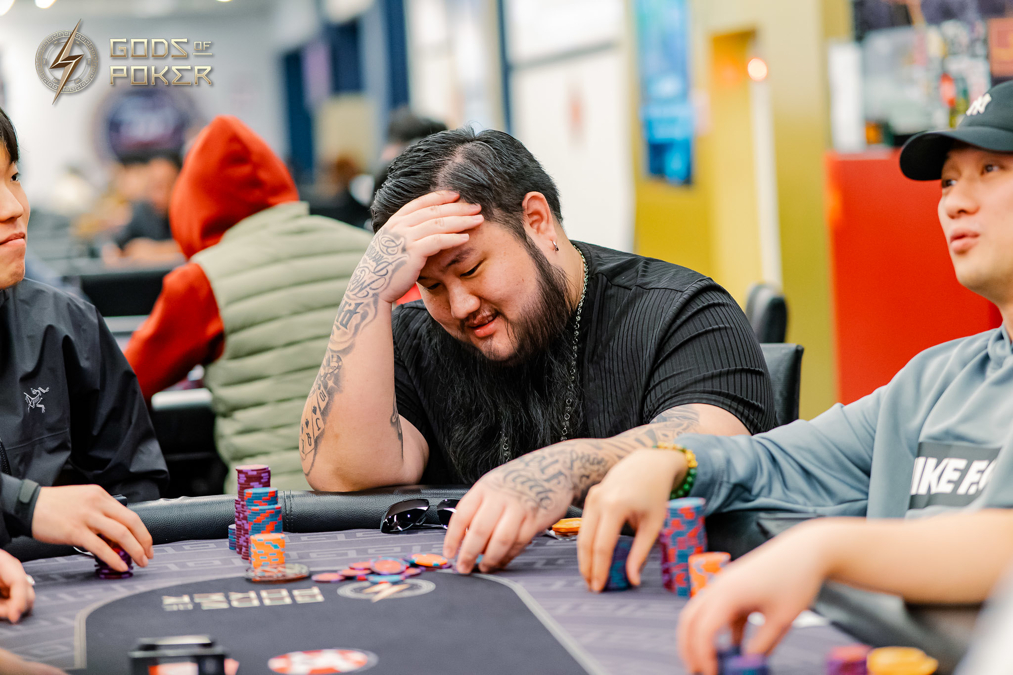 A man at a poker table, head in hand, looking stressed amidst chips.