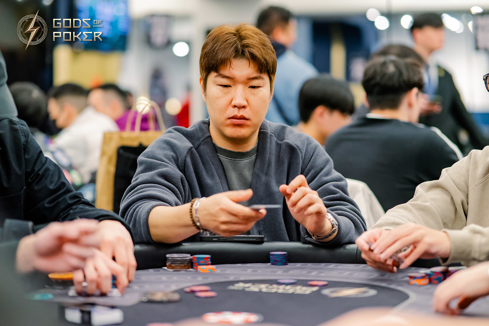 An Asian man intently focuses on his poker chips during a competitive game.