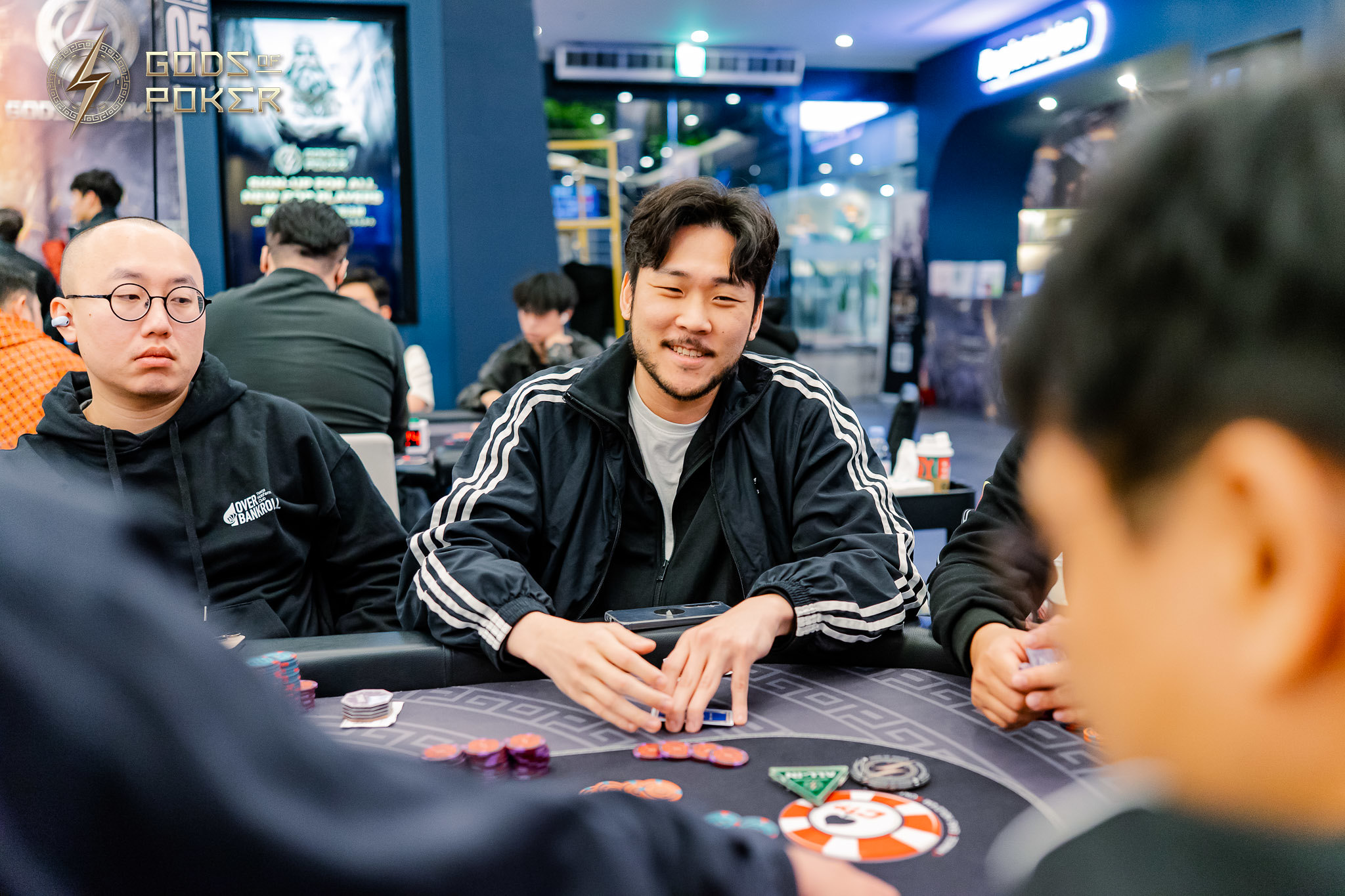 Man in a striped jacket smiling at a poker table with chips and cards.