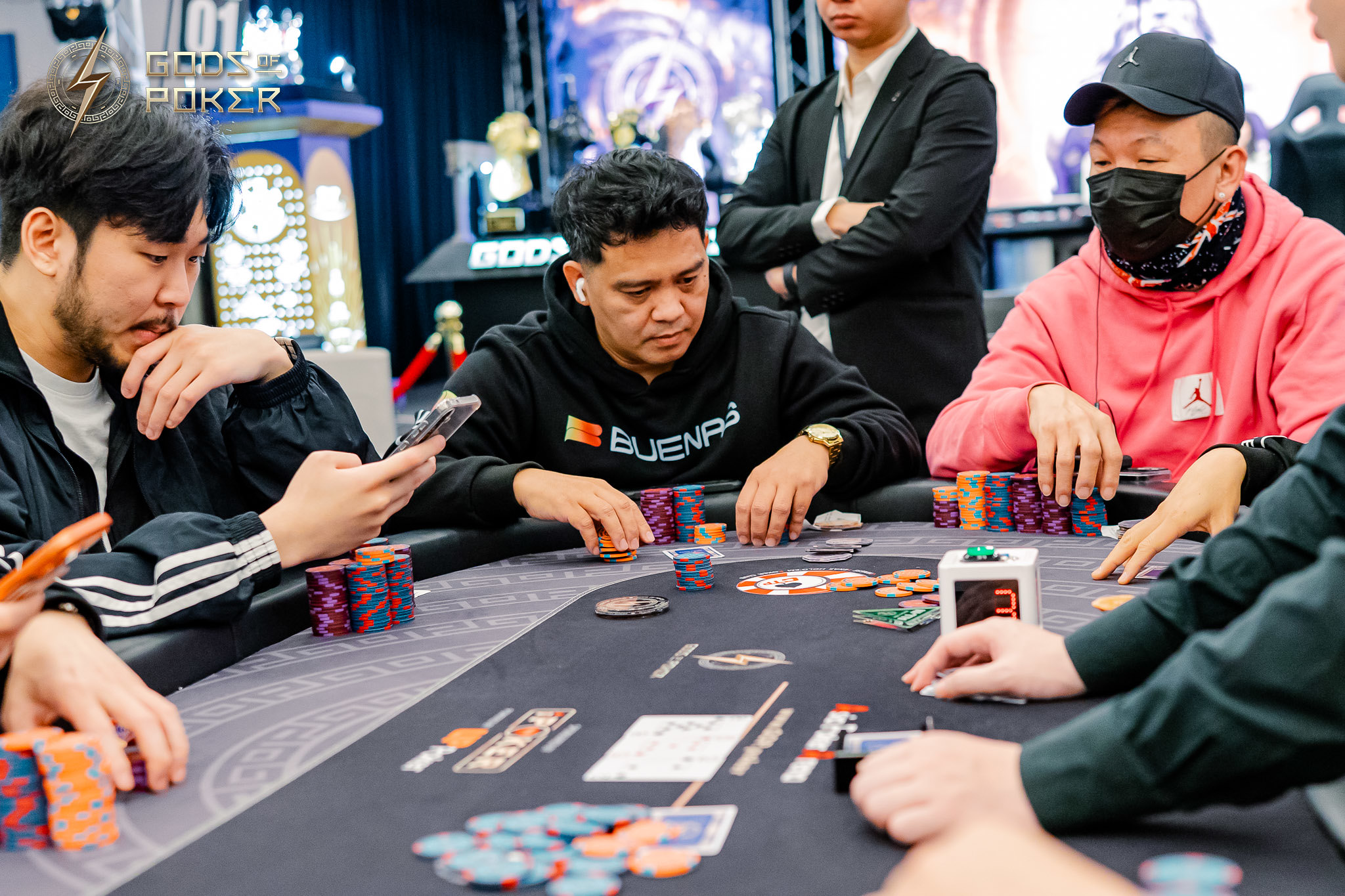 Four men intently playing poker at a table with stacks of chips and cards.