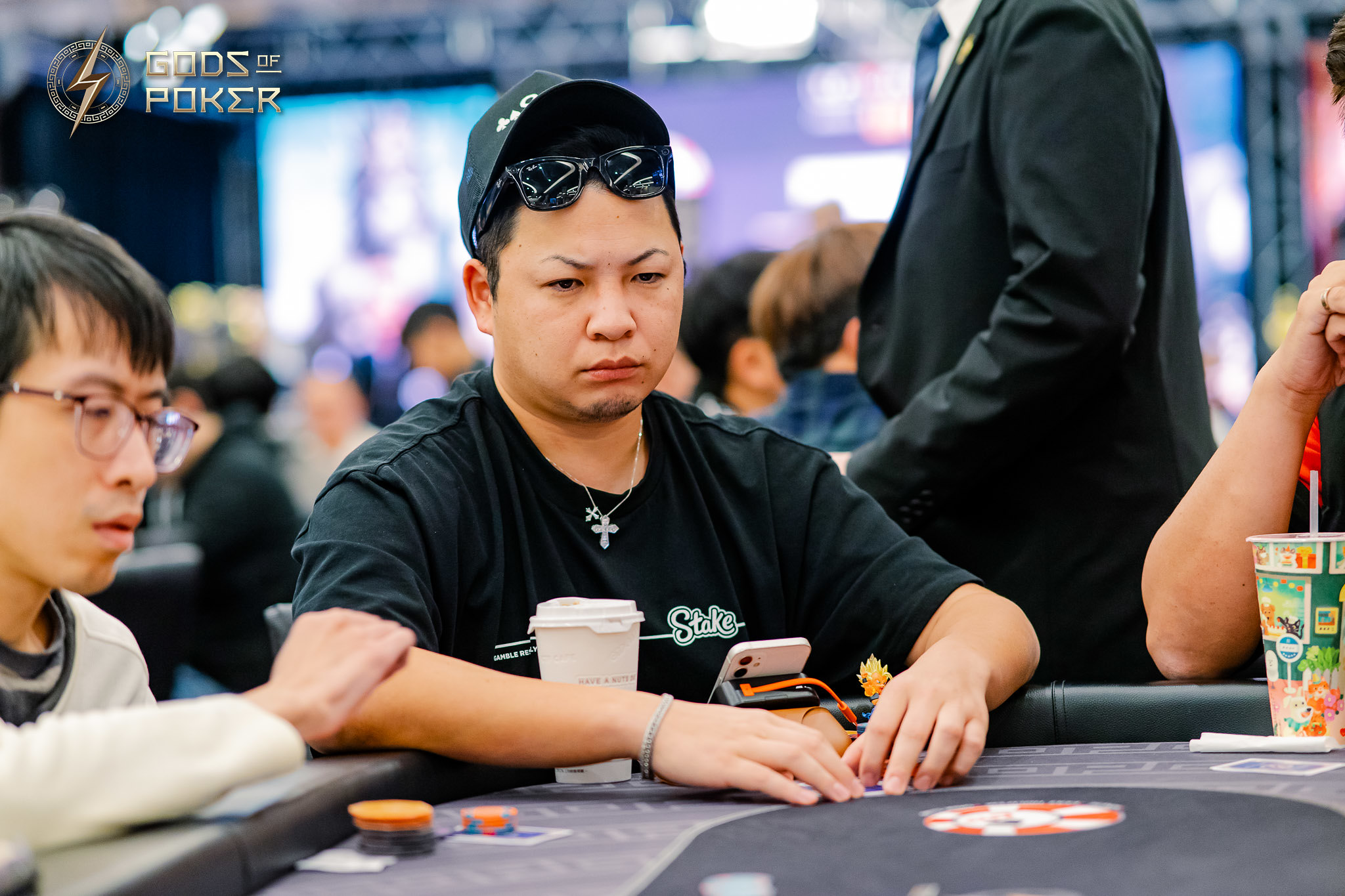 Man with serious expression playing poker at a table with chips and cards.