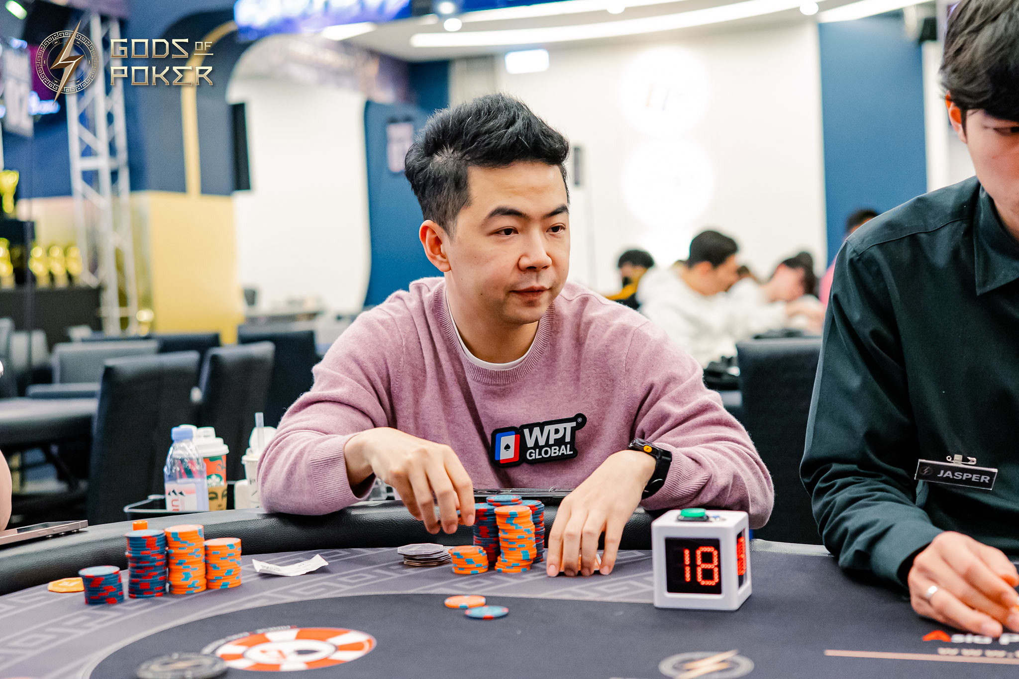 Man in WPT sweatshirt plays poker, handling chips next to a digital timer.