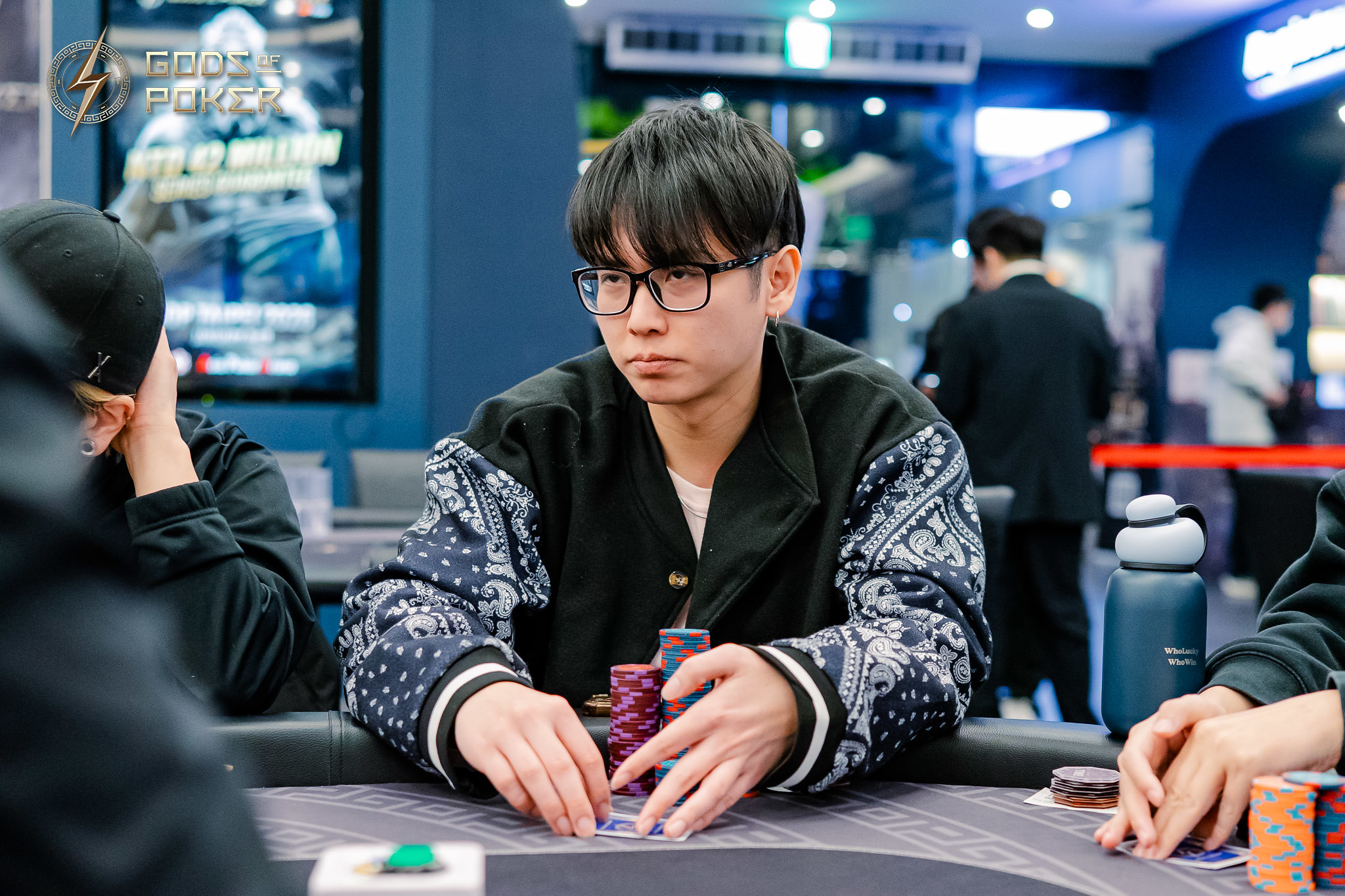 Young man in glasses concentrating, stacking poker chips at a casino table.