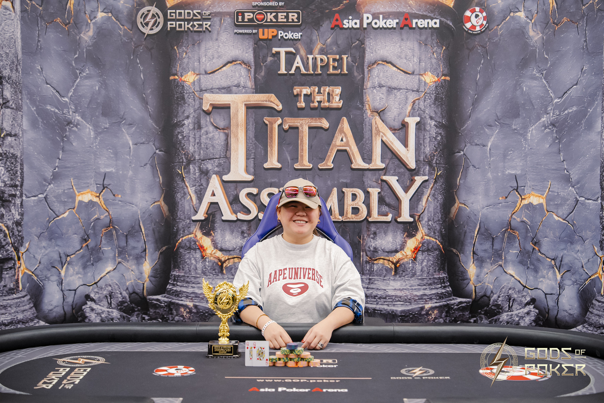 Woman celebrating poker win with chips and trophy at 'The Titan Assembly' event.