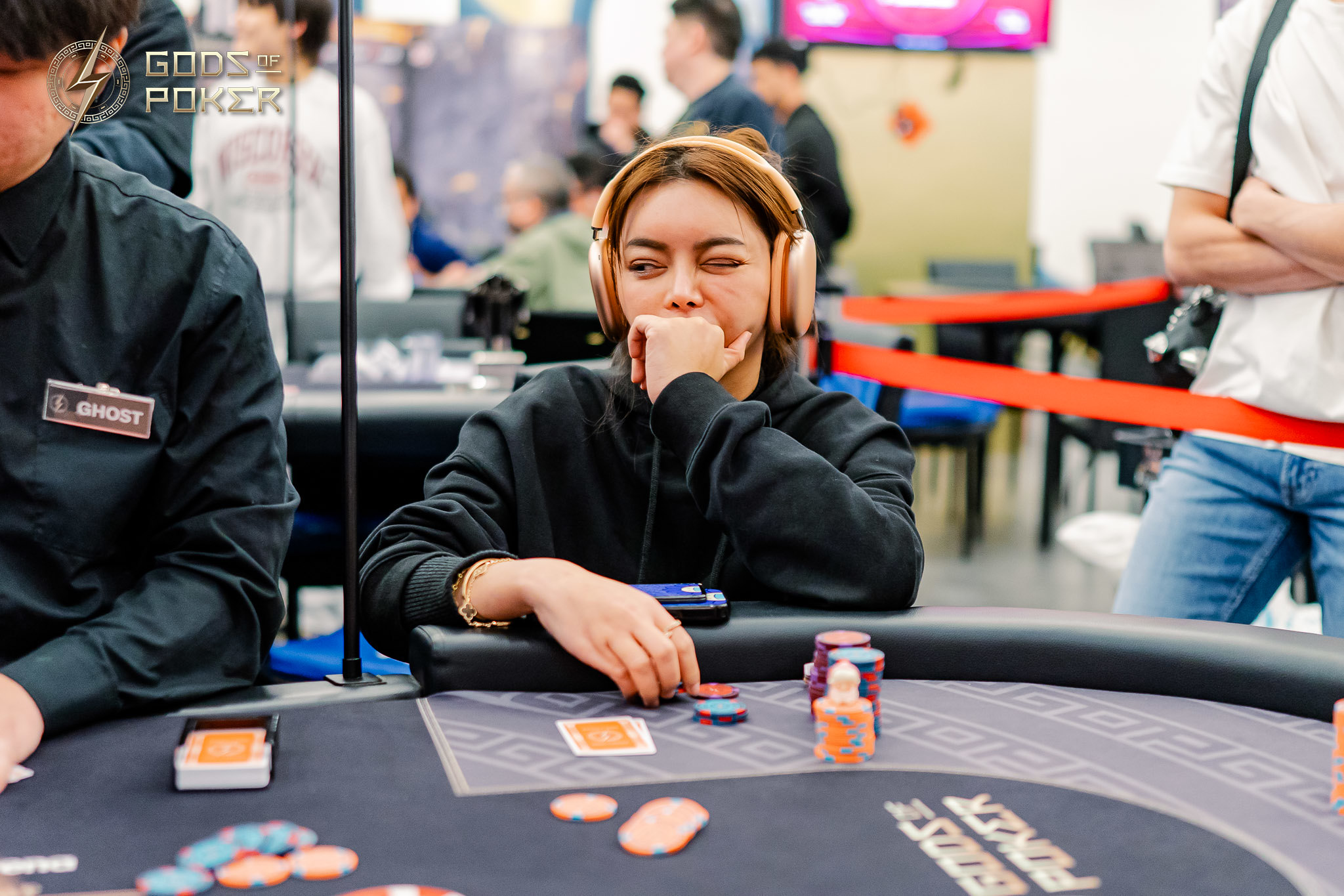 Woman with headphones contemplating her next move at a poker table with chips.