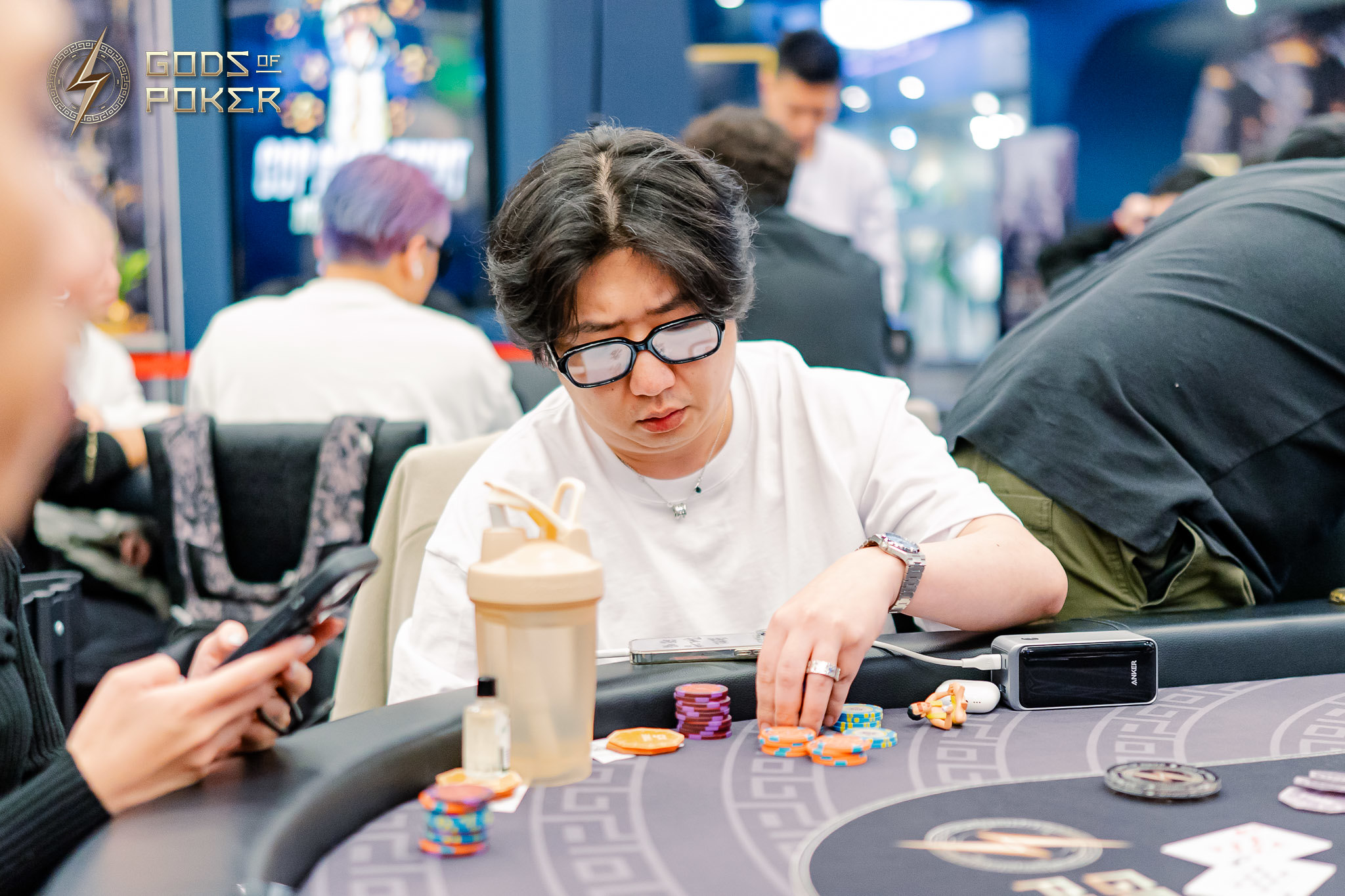 Man in glasses concentrating, playing poker, moving chips at a casino table.
