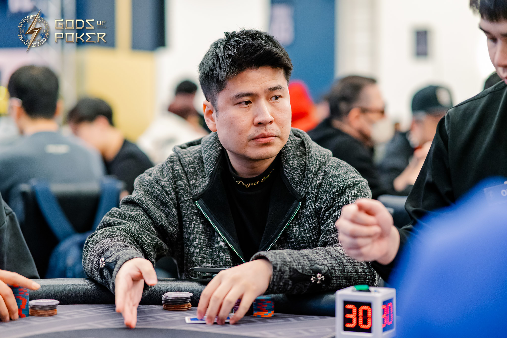 Focused man in a grey jacket plays poker with chips and a 30-second timer.