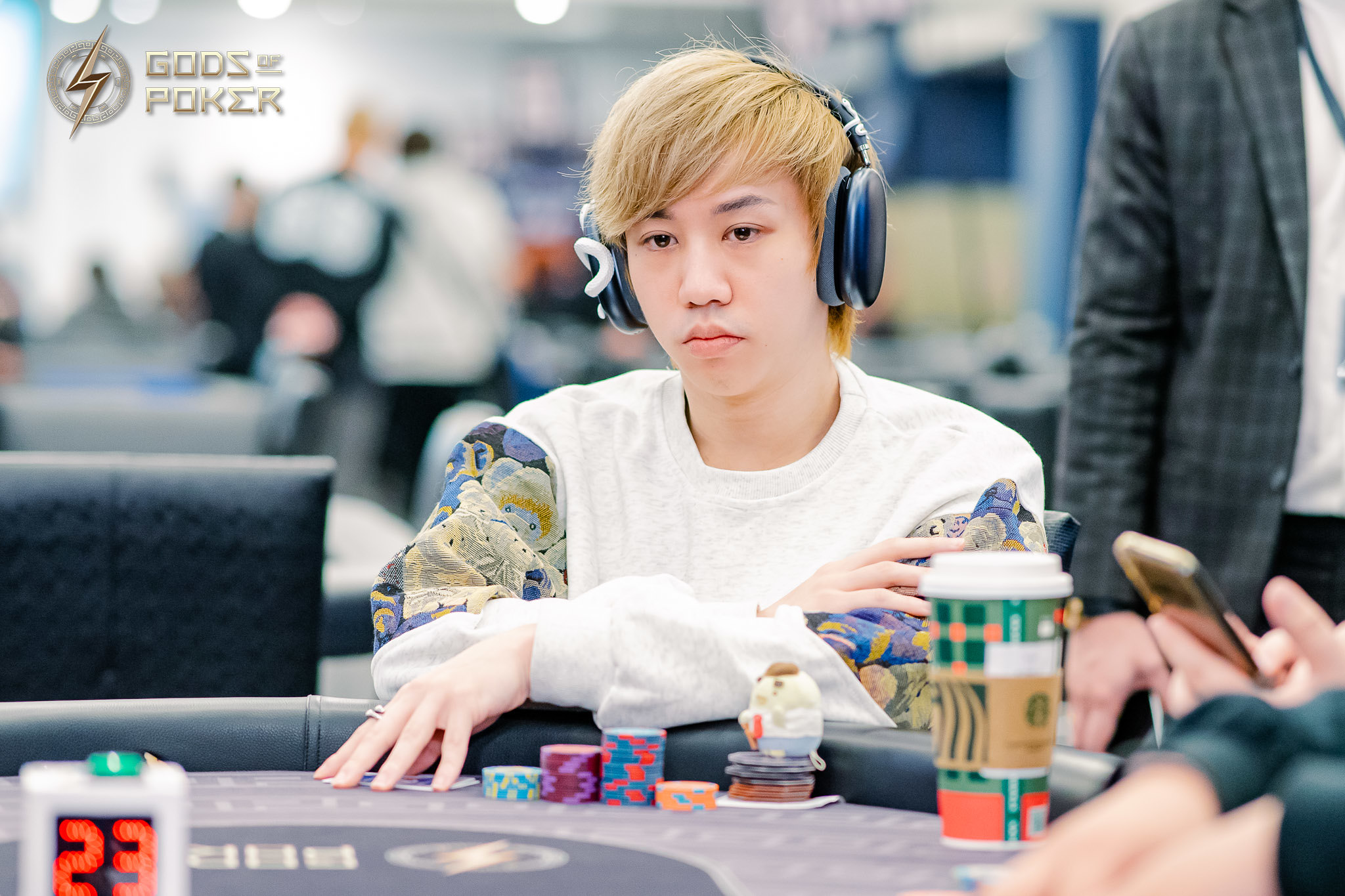 Young man with blonde hair and headphones playing poker at a table.