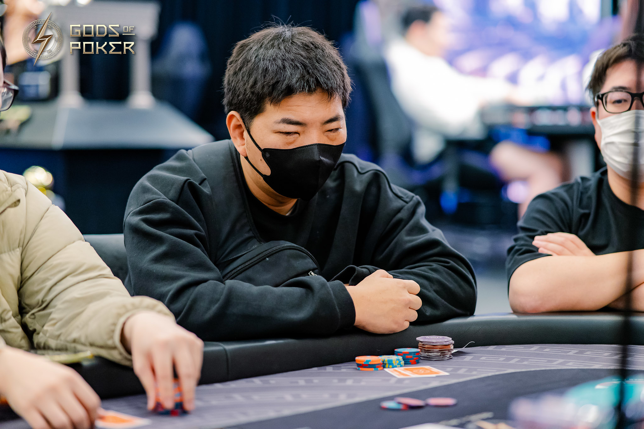 Man in black mask concentrating intently at a poker table with chips.