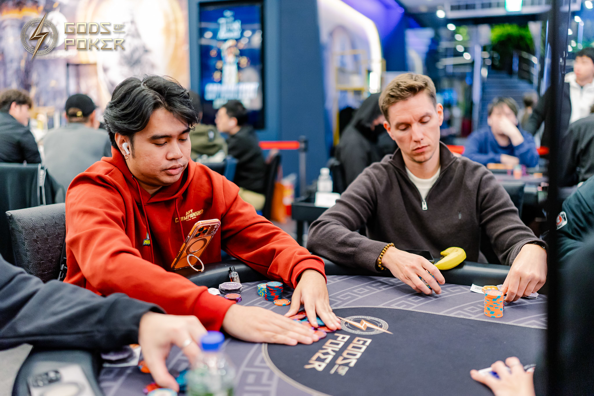 Two men focused on playing poker at a table with chips and cards during a game.