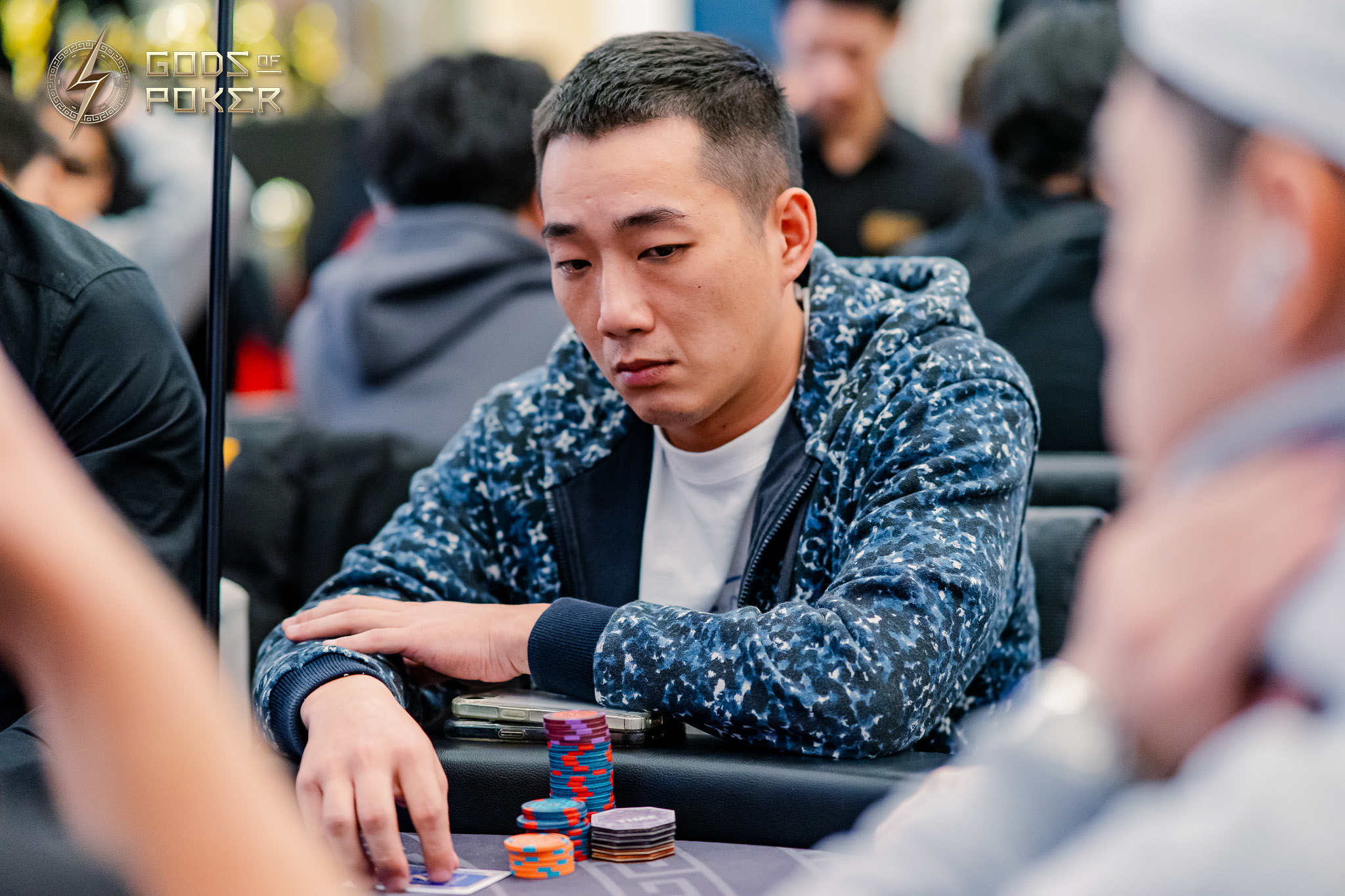 Man in patterned jacket with poker chips and cards at a table.