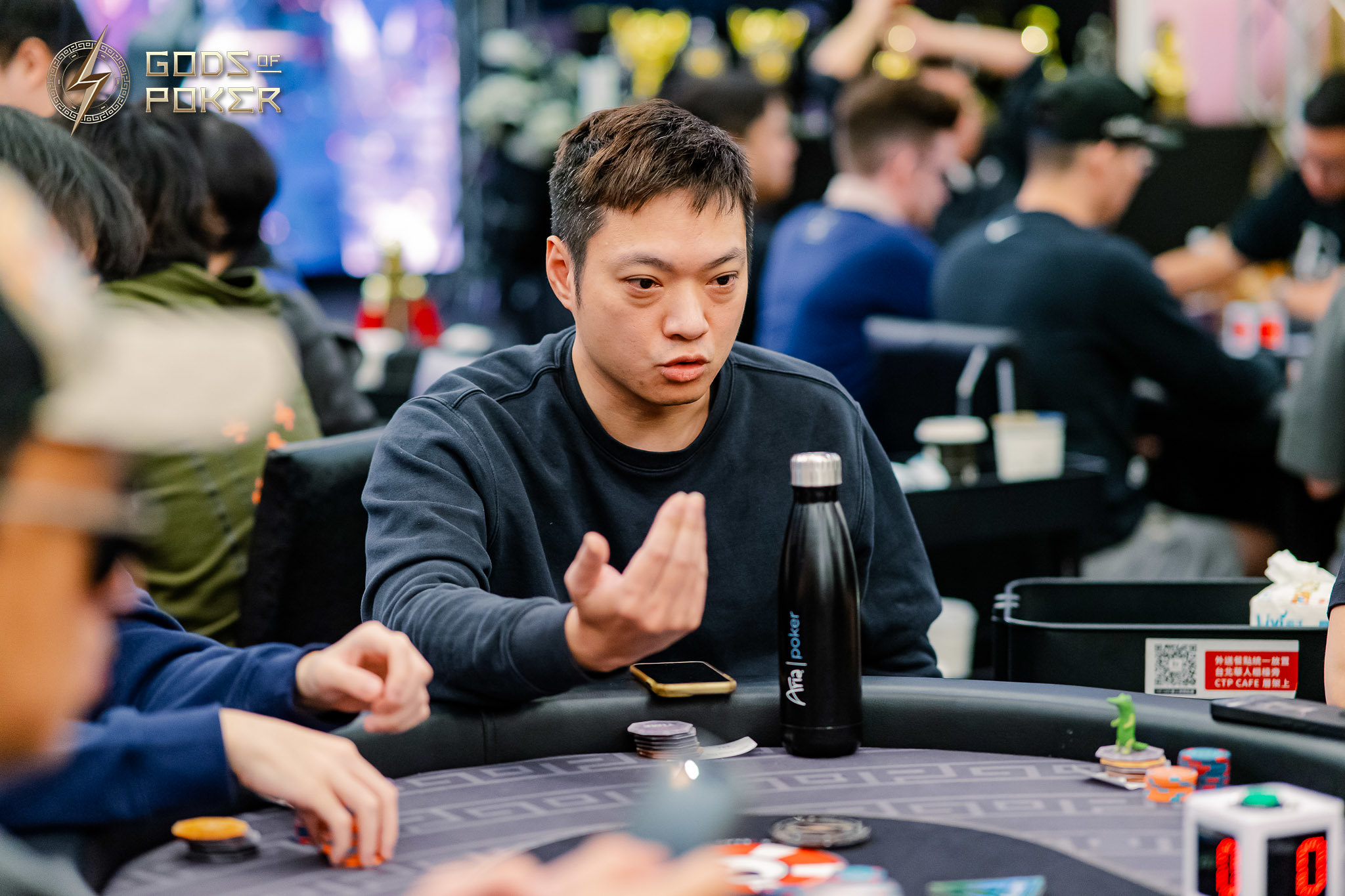 A serious man in a dark shirt contemplates his hand at a poker table.