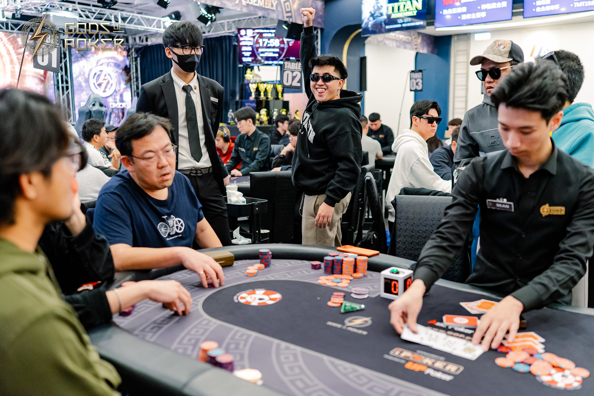 People gathered around a poker table playing cards and interacting in a casino setting.