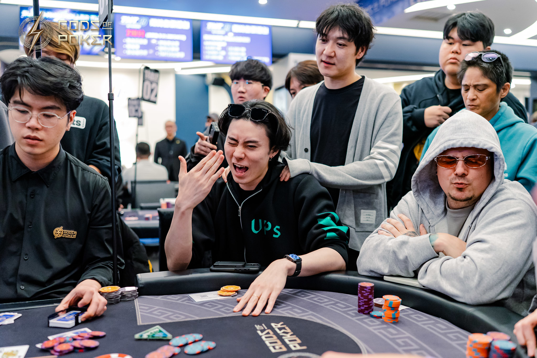 Young poker players react intensely during a game, with one showing strong emotion at the table.