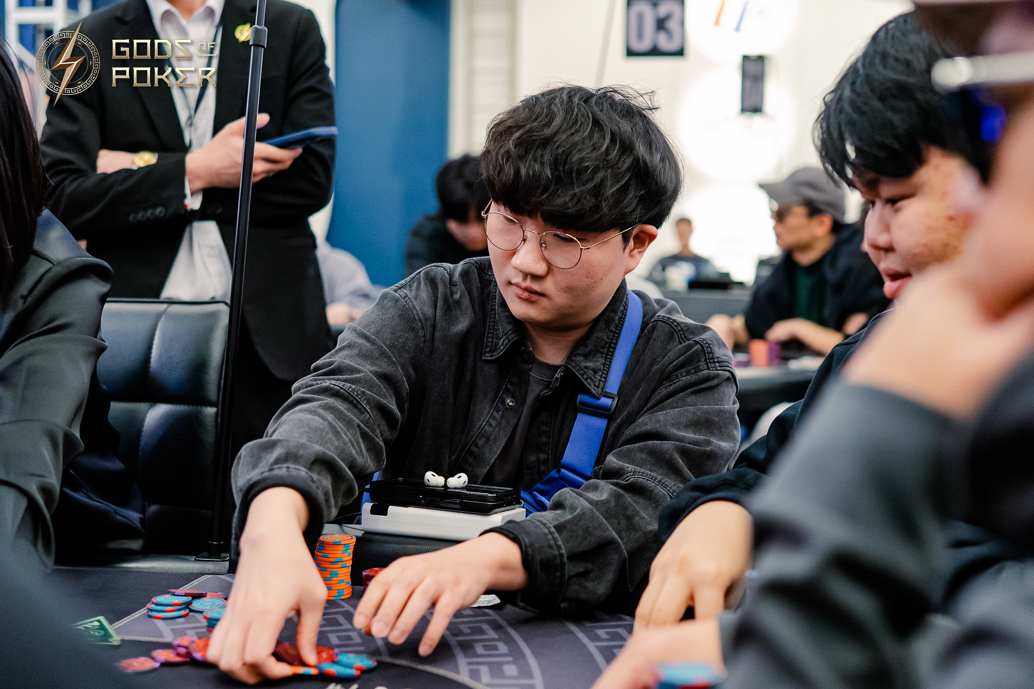 A focused man in glasses plays poker, arranging his chips at a casino table.