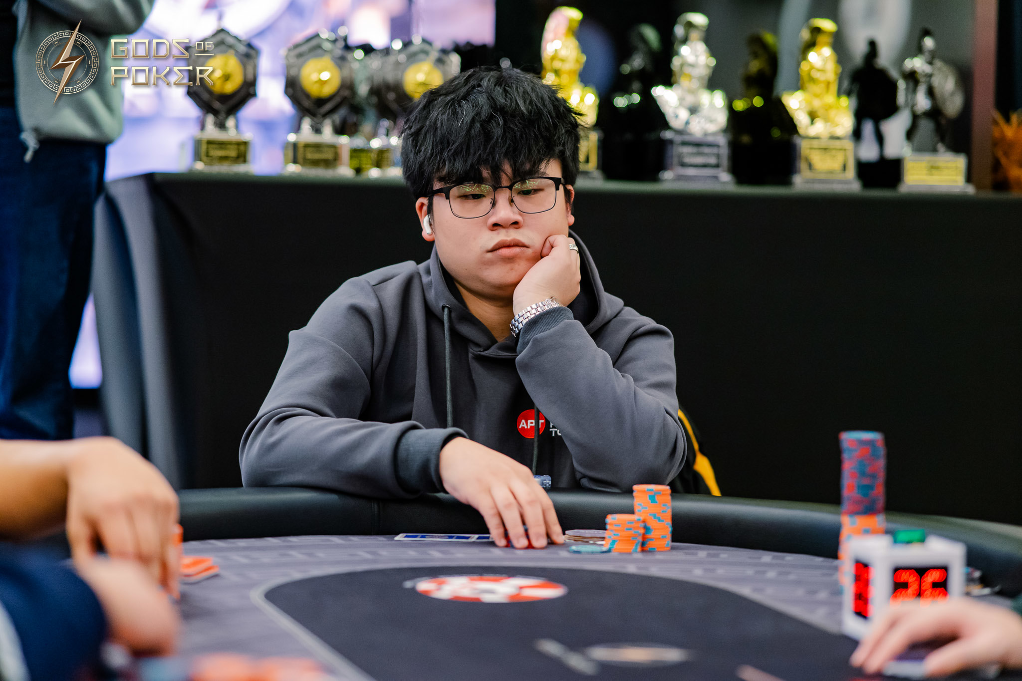 Young man with glasses looking pensive at a poker table with chips.