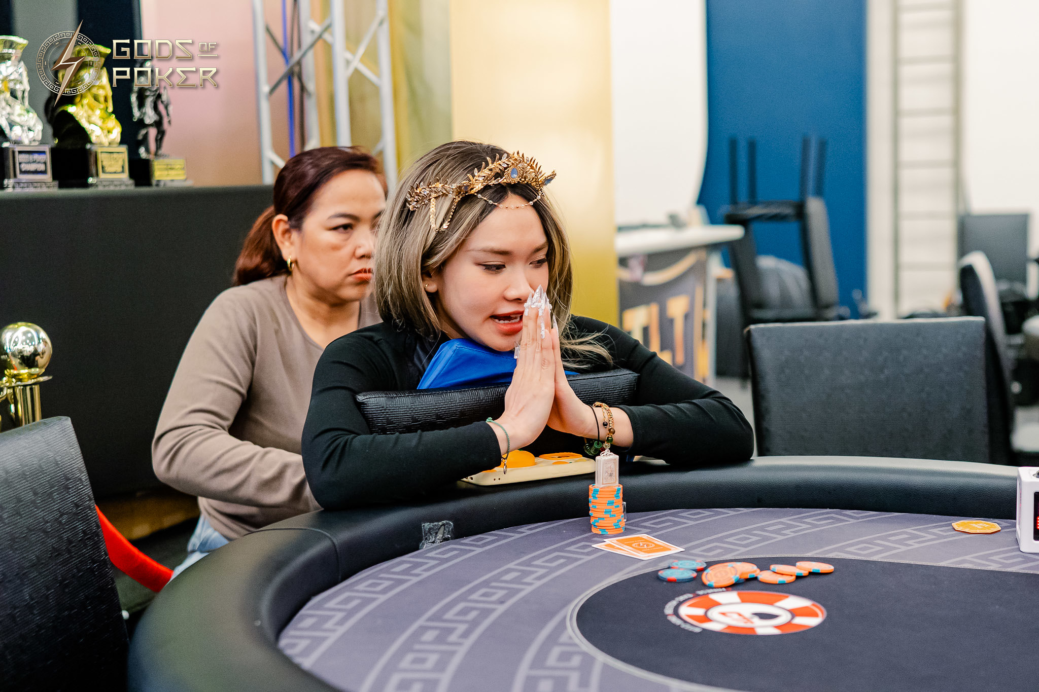 Crowned poker player prays intently at the table with chips and cards.