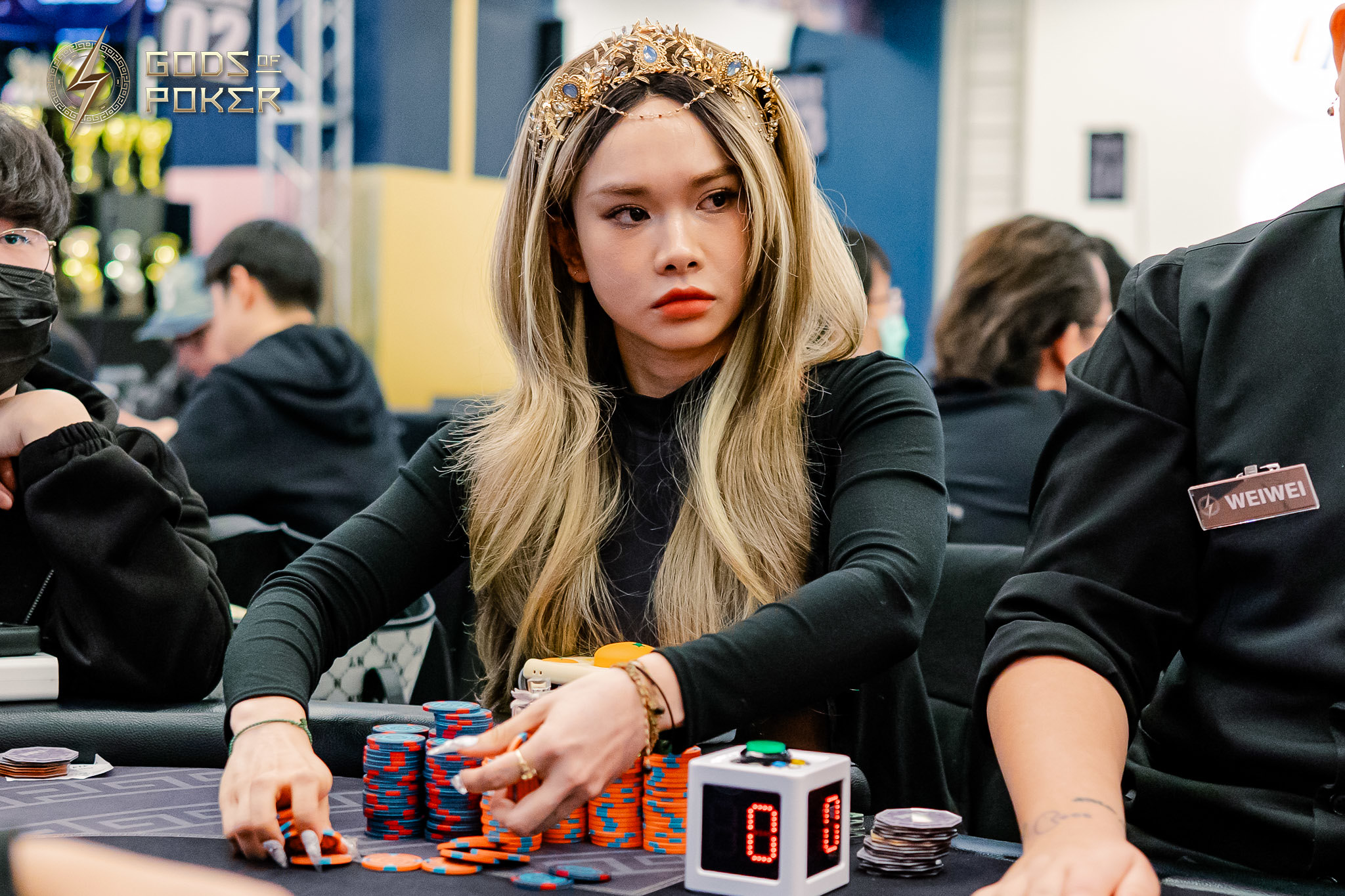 Young woman with long blonde hair stacks poker chips at a table.