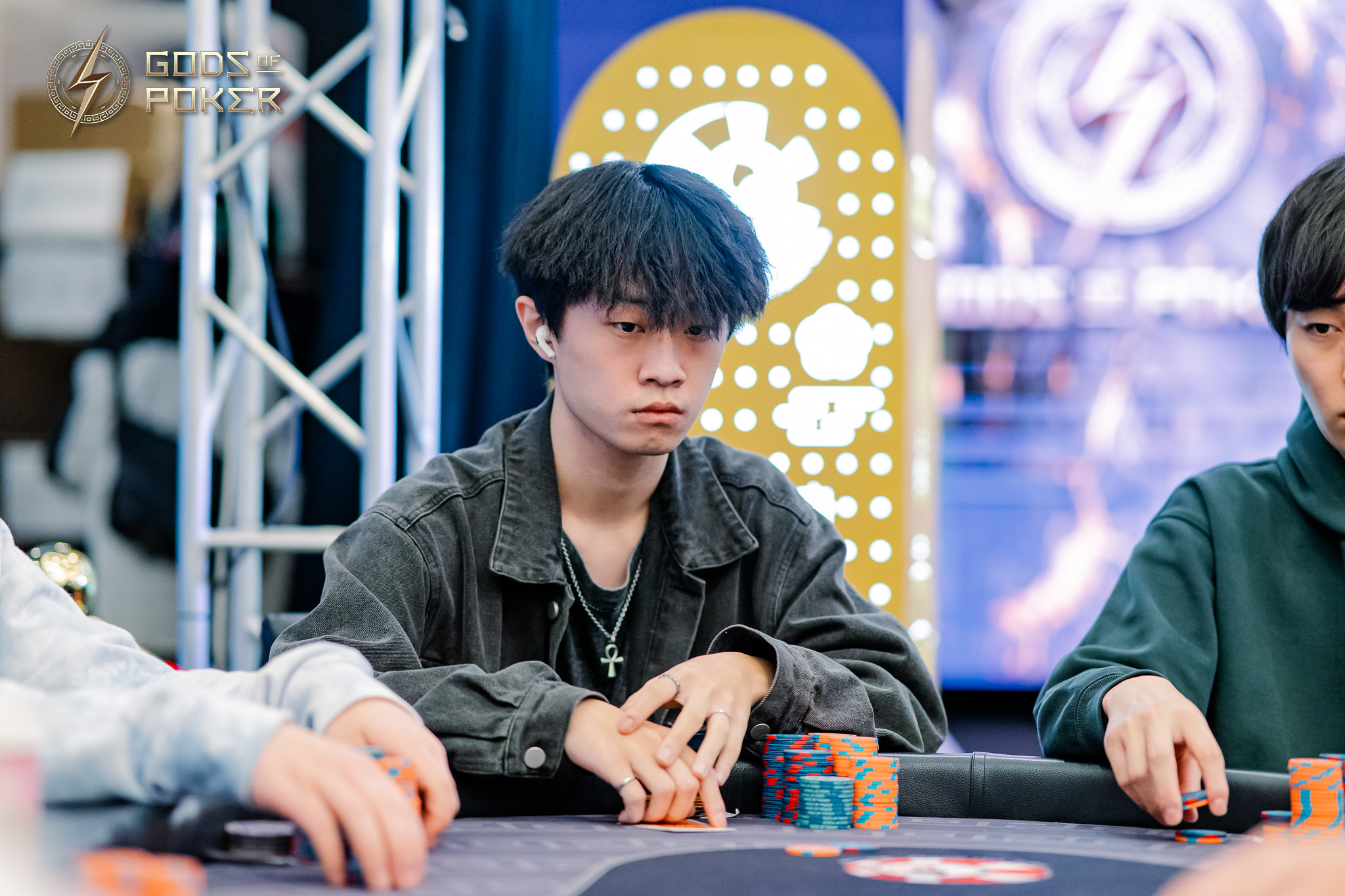 Young man with dark hair, serious expression, playing poker with chips on a table.