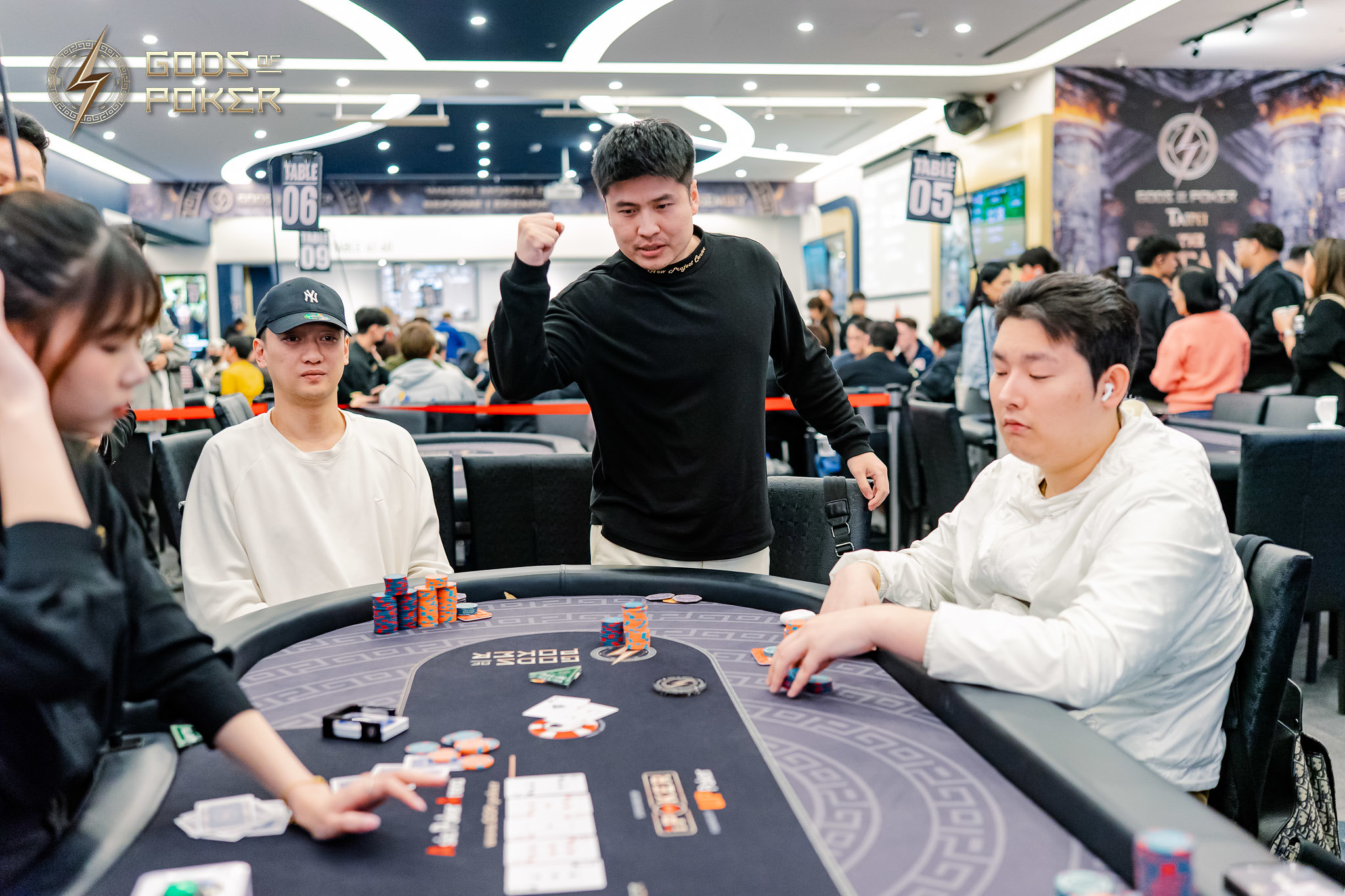 Man celebrates excitedly at a poker table surrounded by players and casino chips.