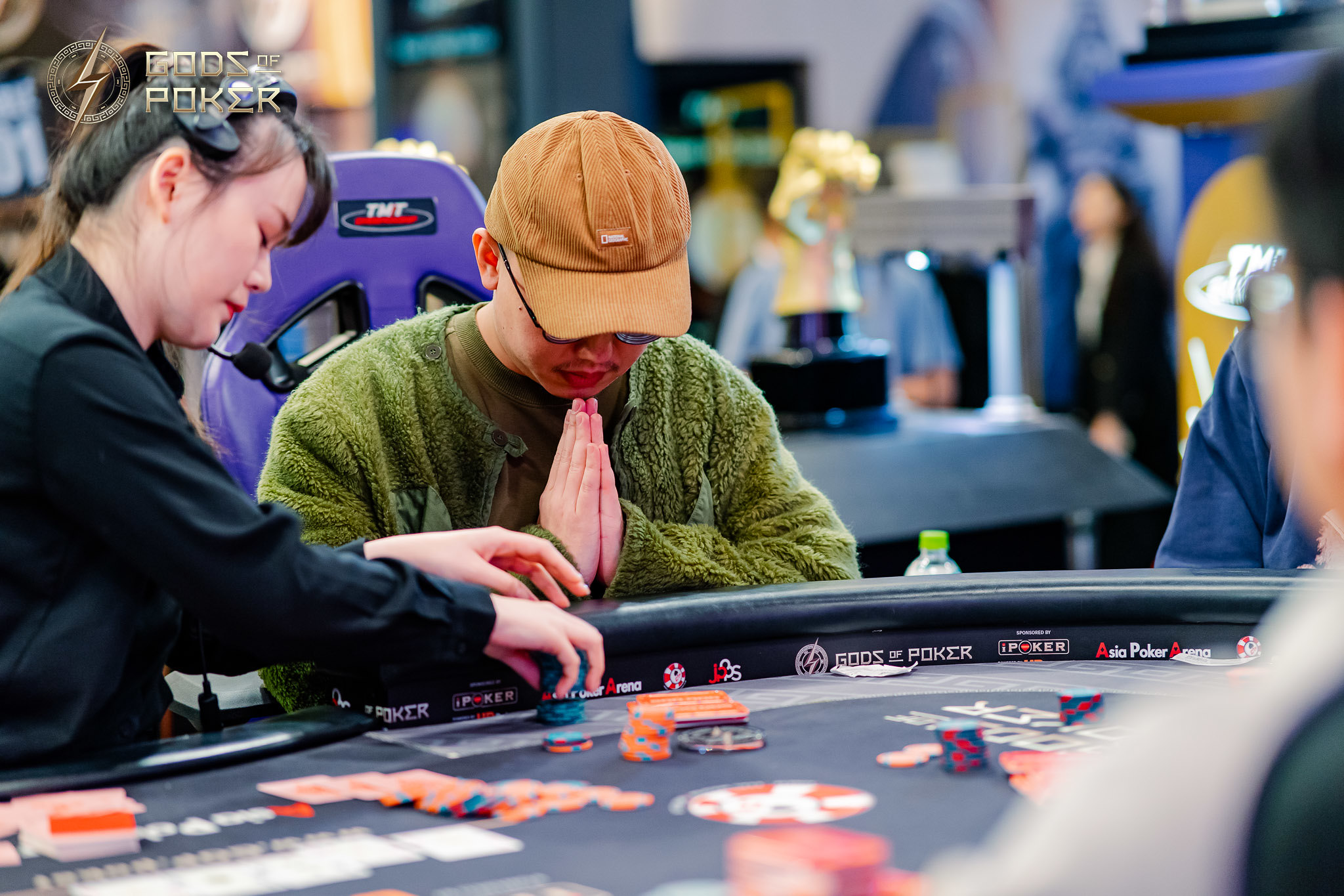 Poker players: a woman handling chips and a man in a cap at the table.