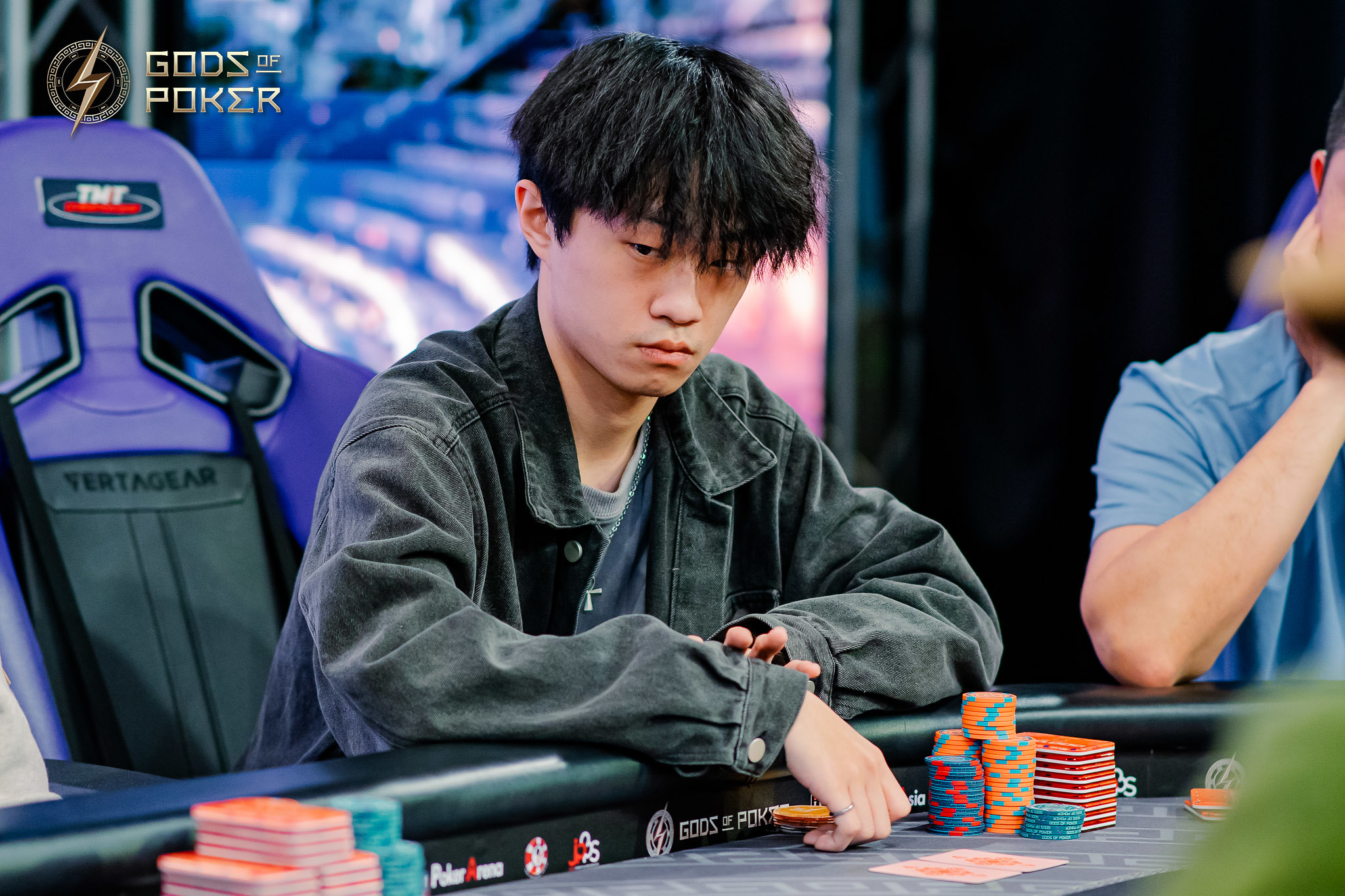 Young man intently playing poker, surrounded by chips at a gaming table.