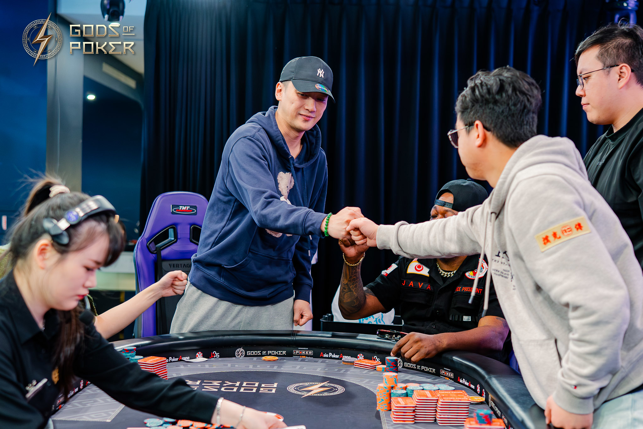 Two men fist-bumping at a poker table while other players watch.