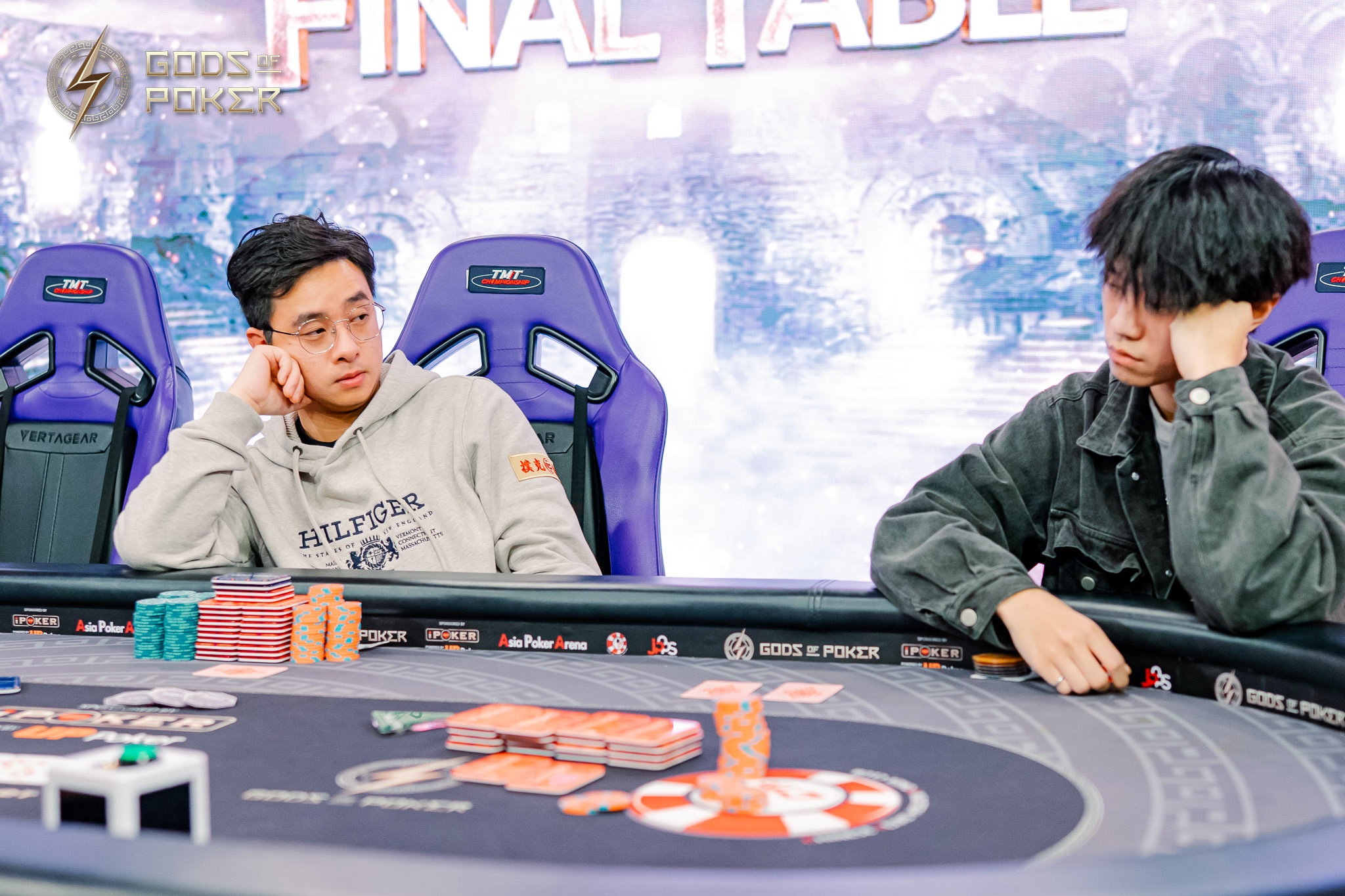 Two men looking pensive at a poker final table with chips.