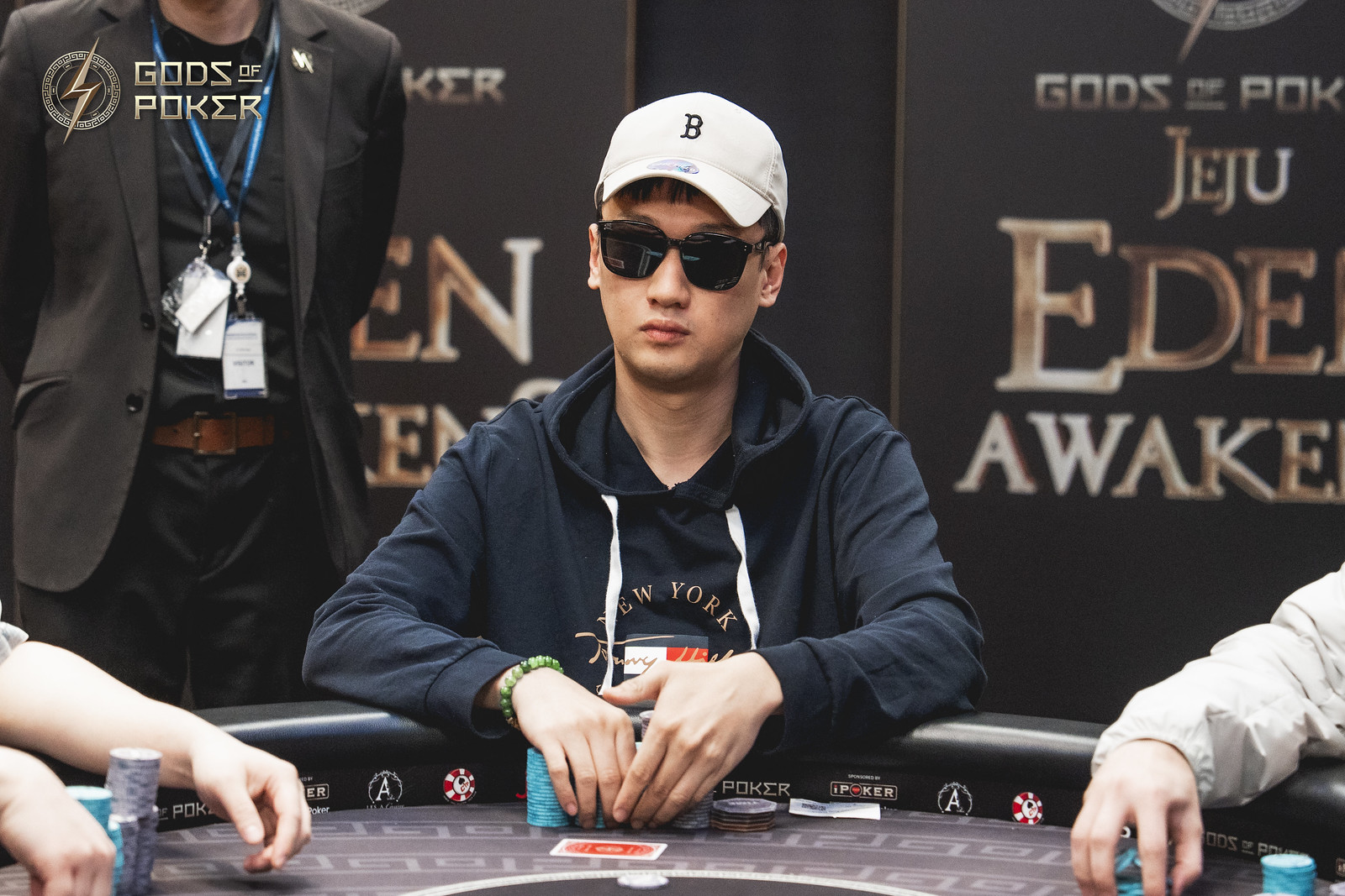 Young man in sunglasses and cap playing poker at a casino table.