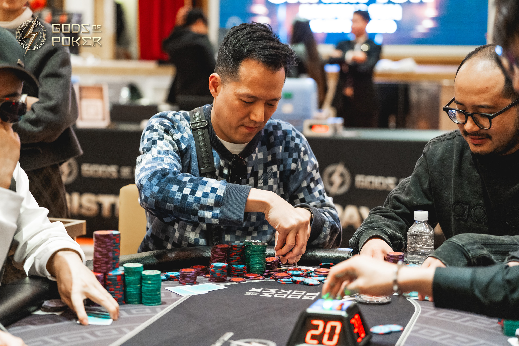 Man in patterned shirt playing poker, pushing chips into the pot at a casino.