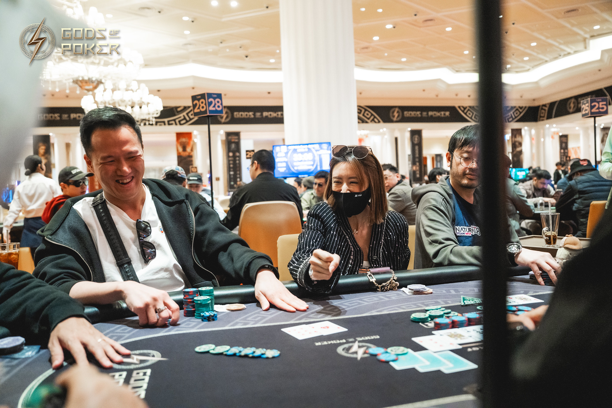A man smiles broadly while playing poker at a casino table with other players.
