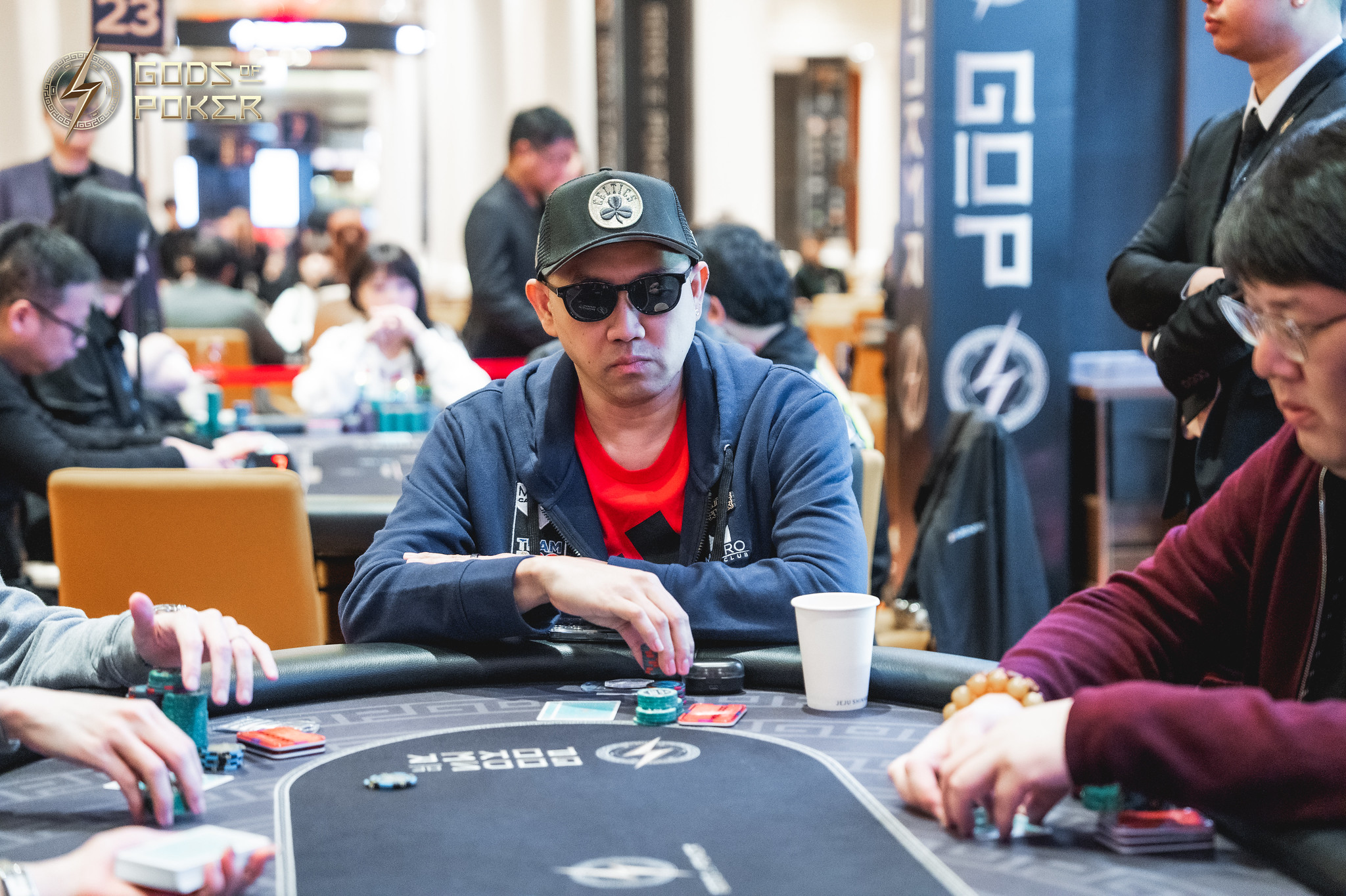 Man in sunglasses and a cap intently plays poker at a casino table.
