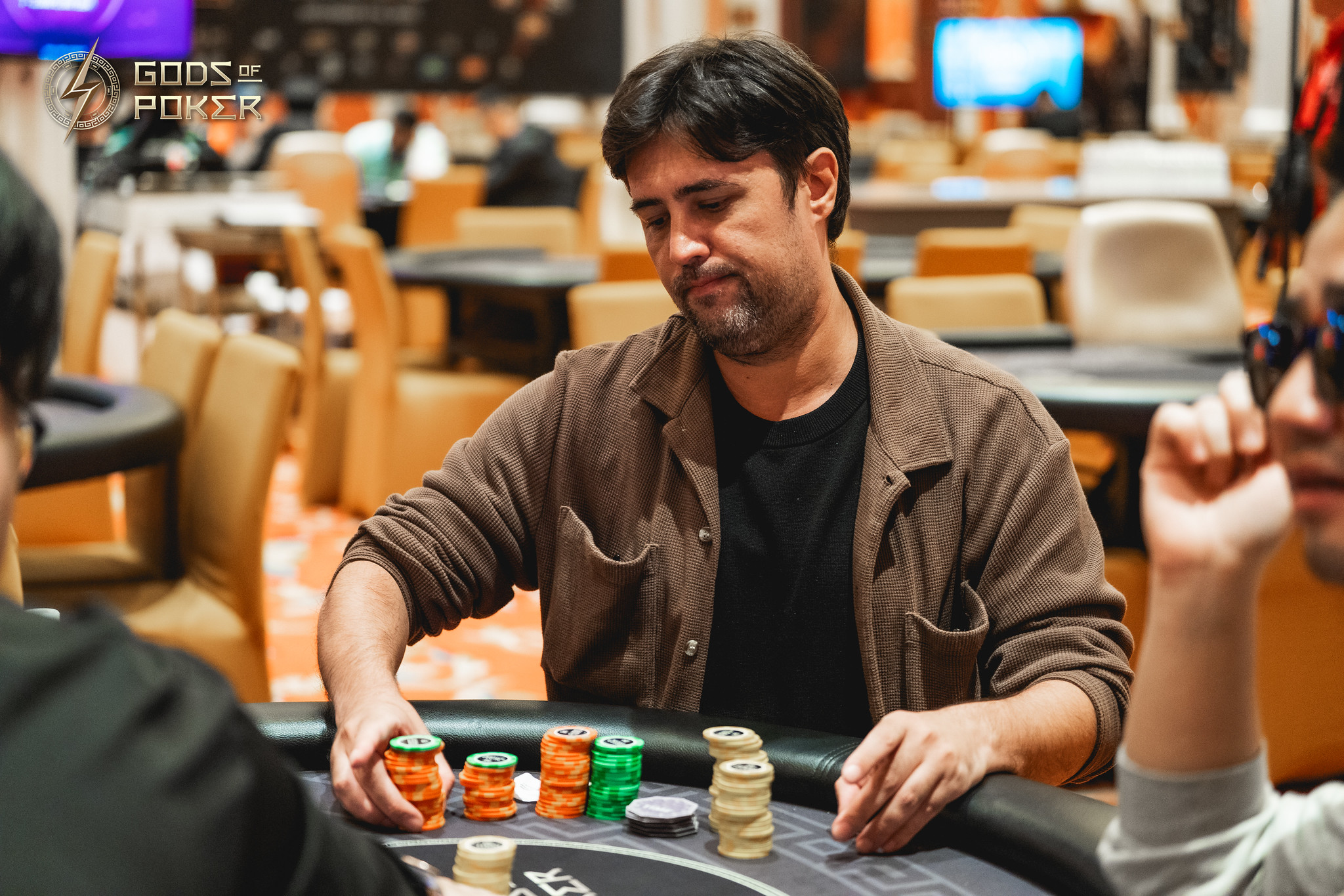 Man at a poker table arranging his stack of chips during a high-stakes game.