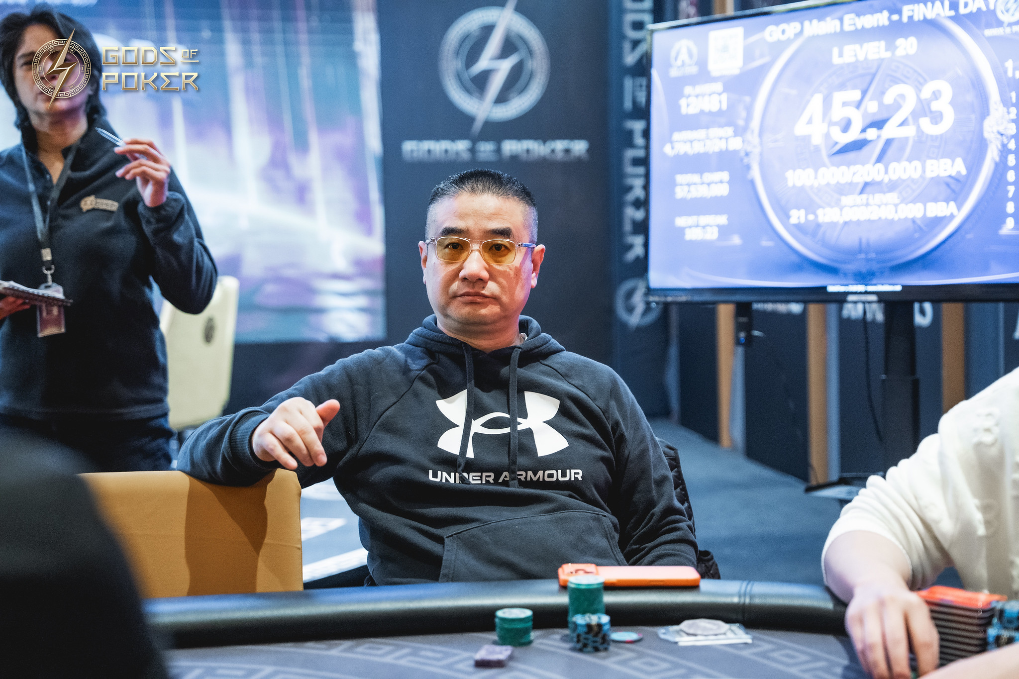 A man in a black hoodie sits intently at a poker table with chips.