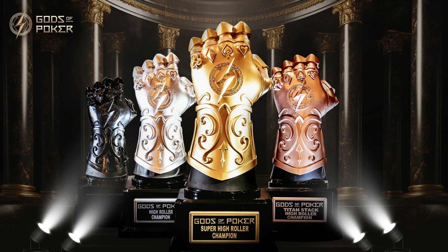Four ornate gauntlet trophies in black, silver, gold, and bronze on a spotlighted stage.
