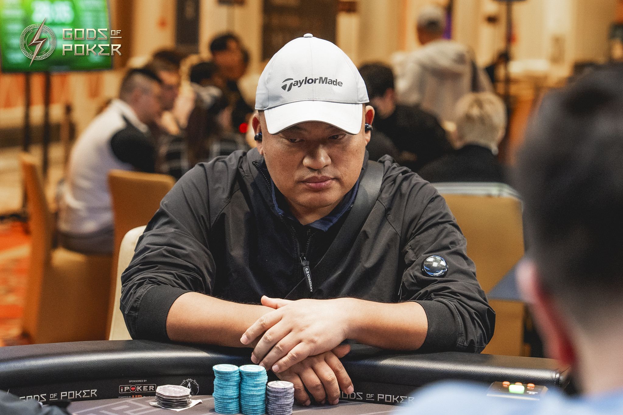 Man in a white cap intently playing poker at a table with chips.