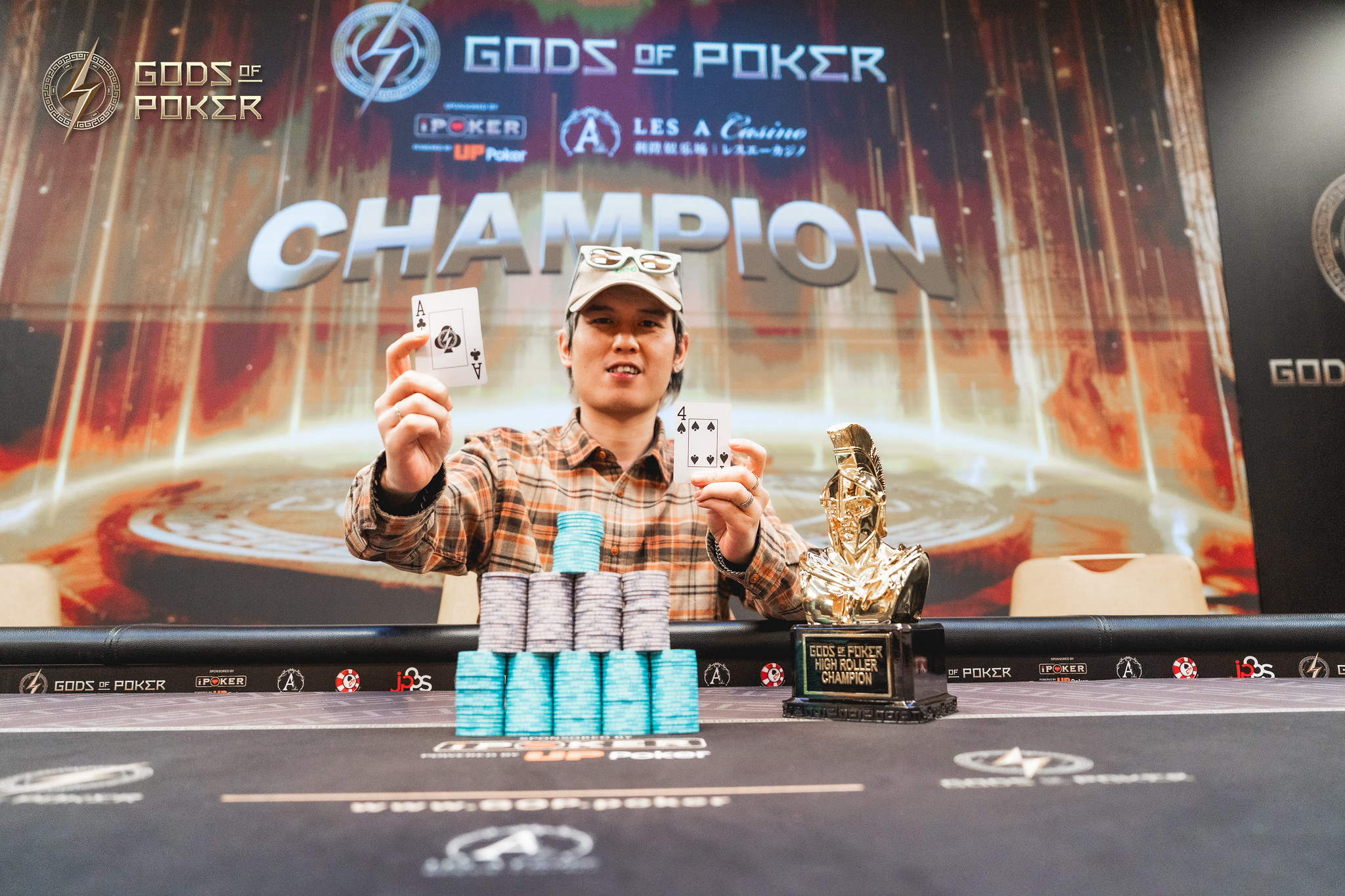 Man celebrates poker victory, holding two aces and standing before a