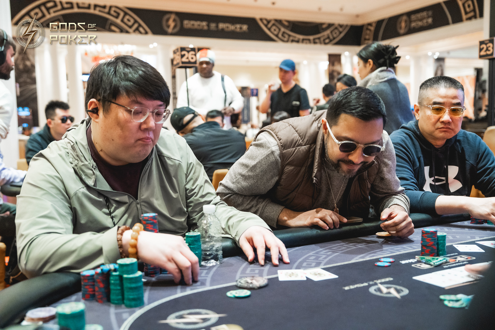 Three men intensely focused, playing poker at a casino table with chips and cards.
