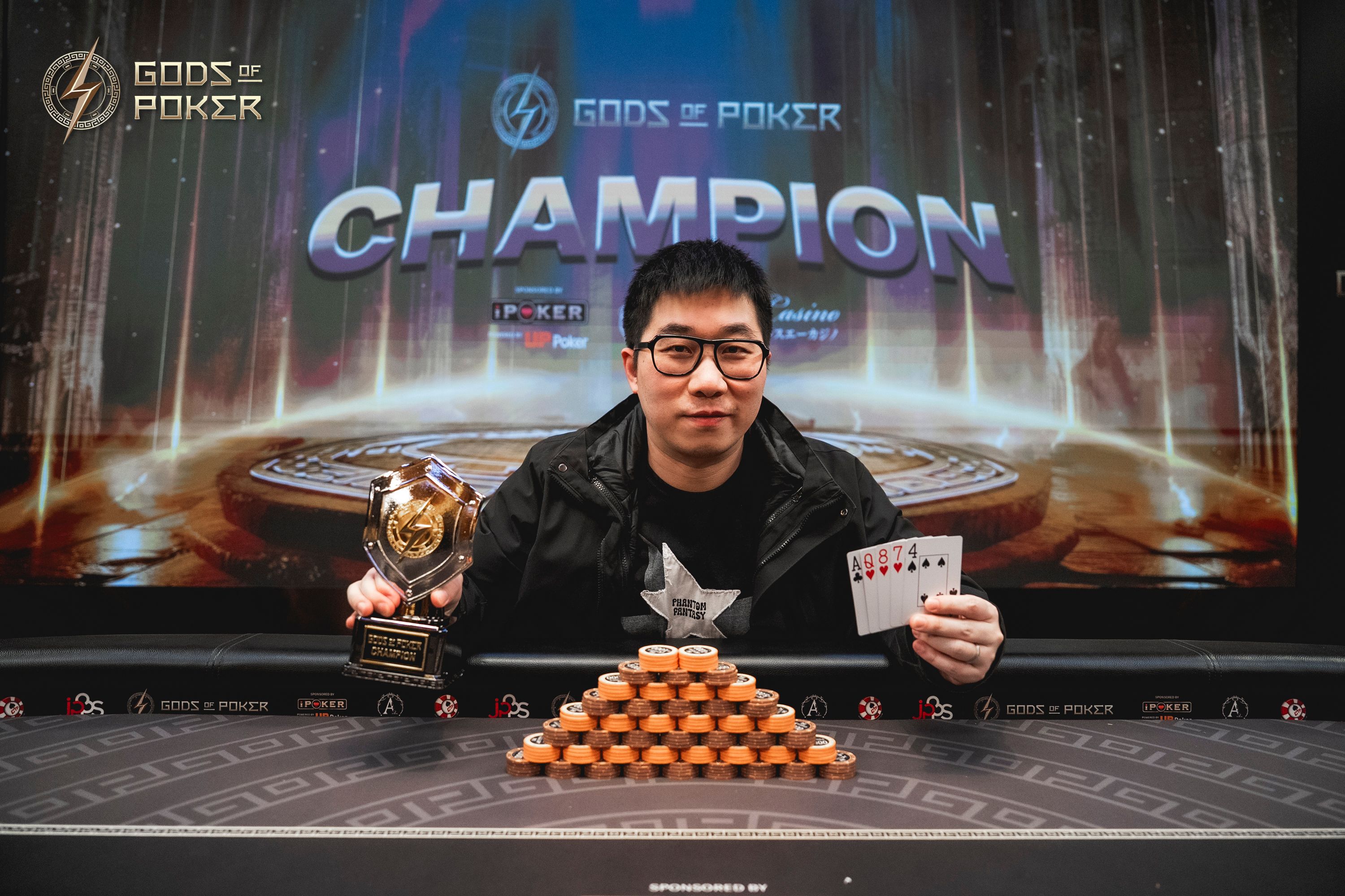 A poker champion proudly displays his trophy and winning cards after a game.