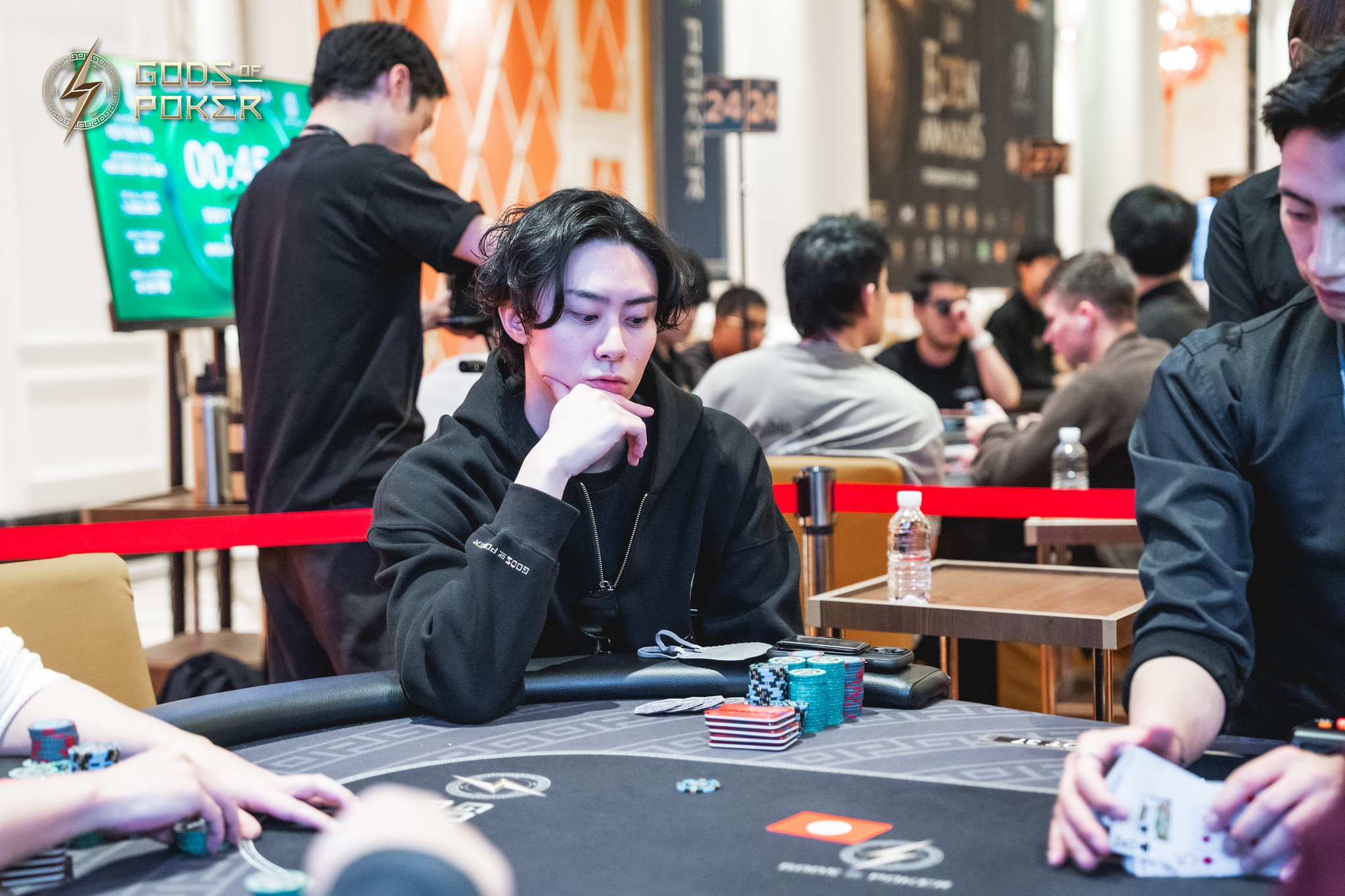 Young man in black hoodie intently playing poker at a casino table.