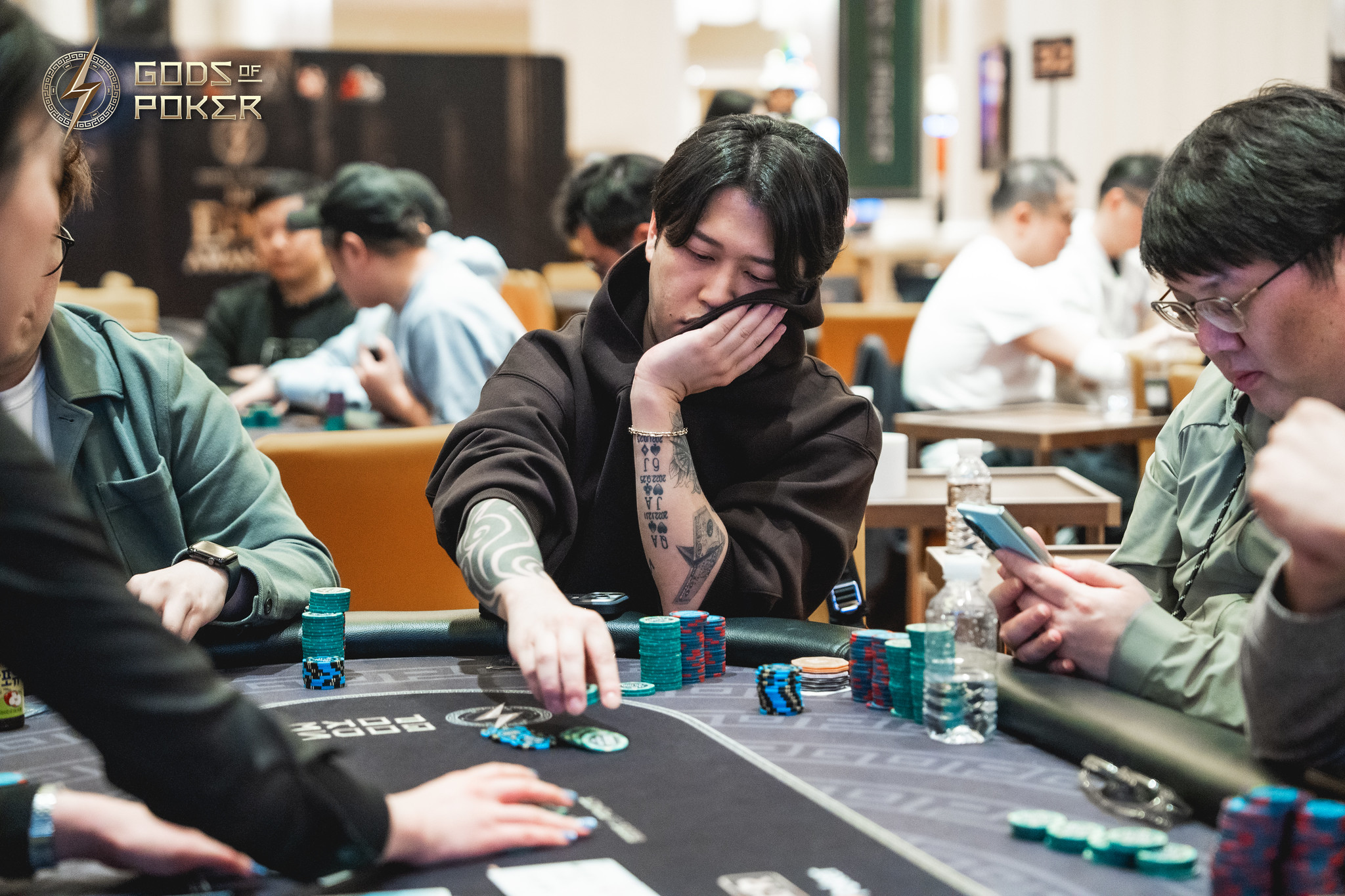 A man with tattoos contemplating his move at a poker table.