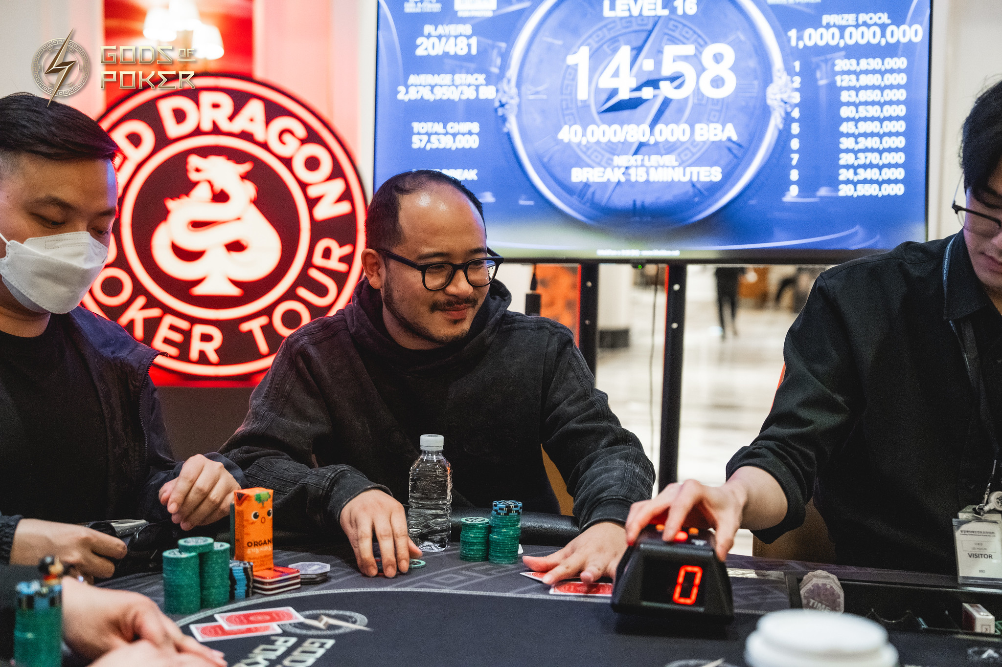 Men playing poker with chips and cards at a table during a tournament.