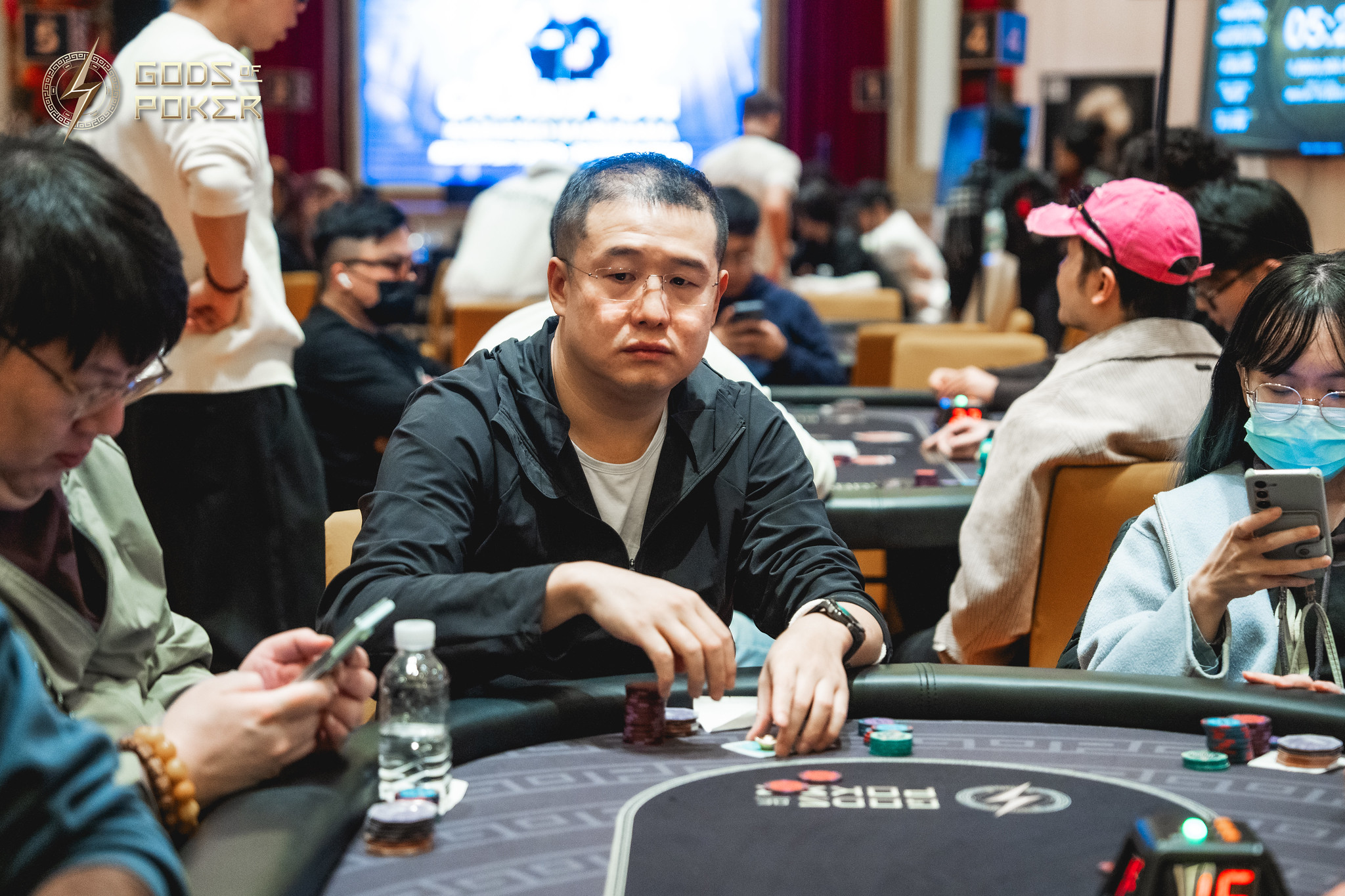 A man with a serious expression sits at a poker table during a game.